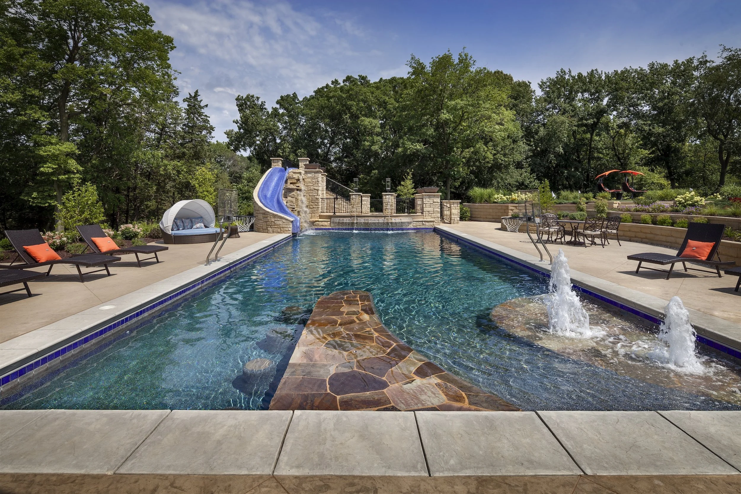 Luxury backyard with pool, water slide, lounge chairs, and trees