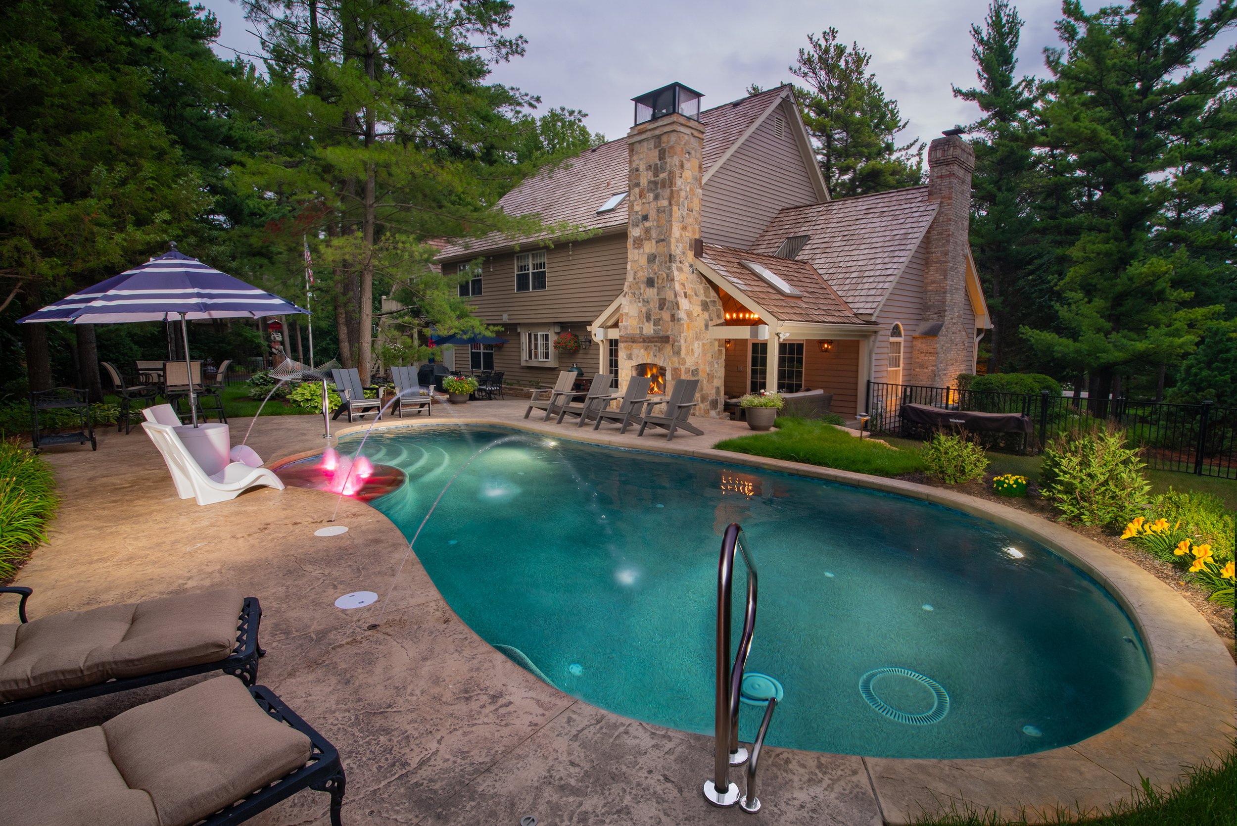 Luxury backyard pool built by Barrington Pools in Geneva Illinois water features, tanning ledge, pebbletec pool finish