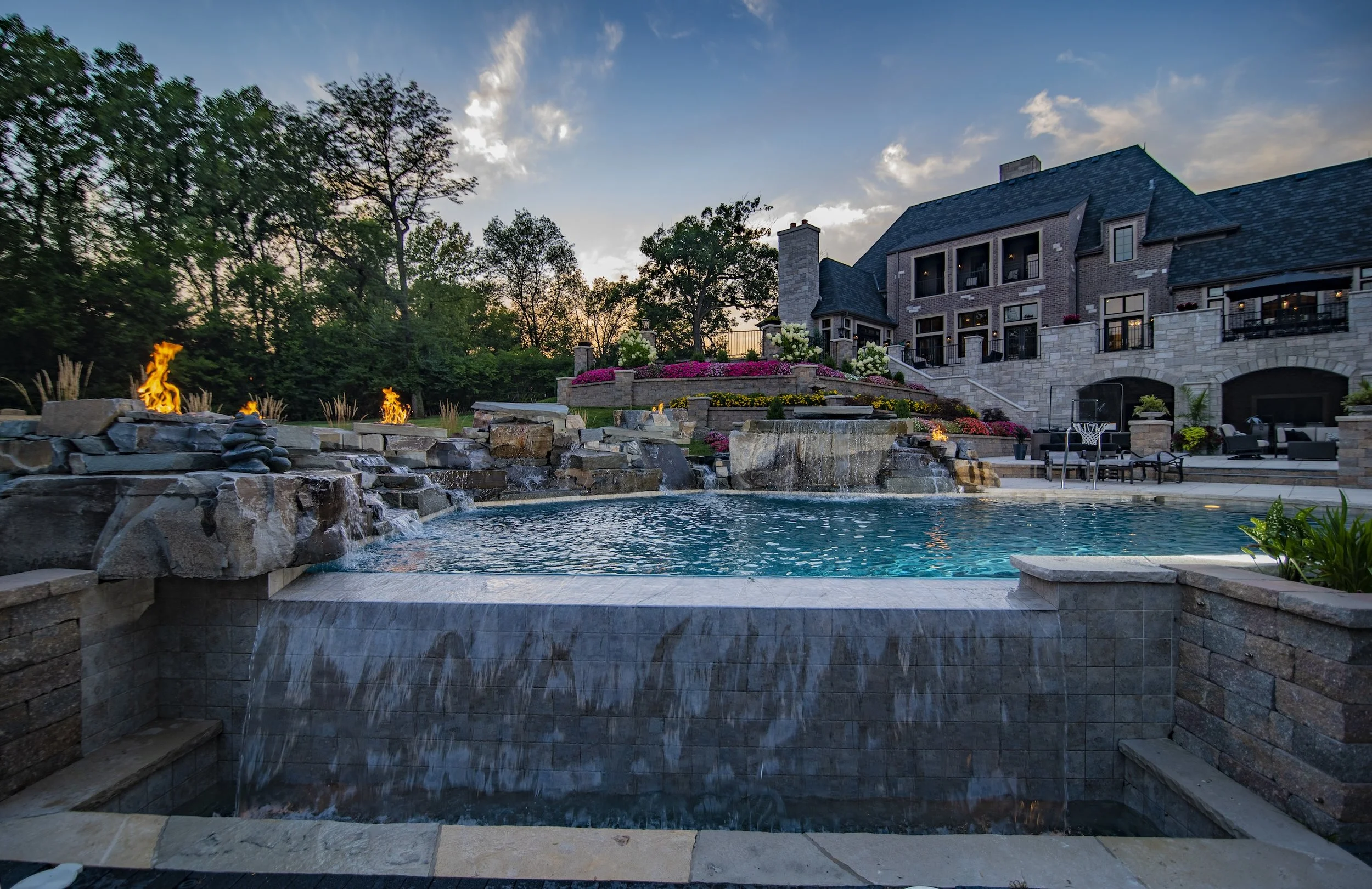 Luxury backyard with pool, waterfall, fire features, and large house