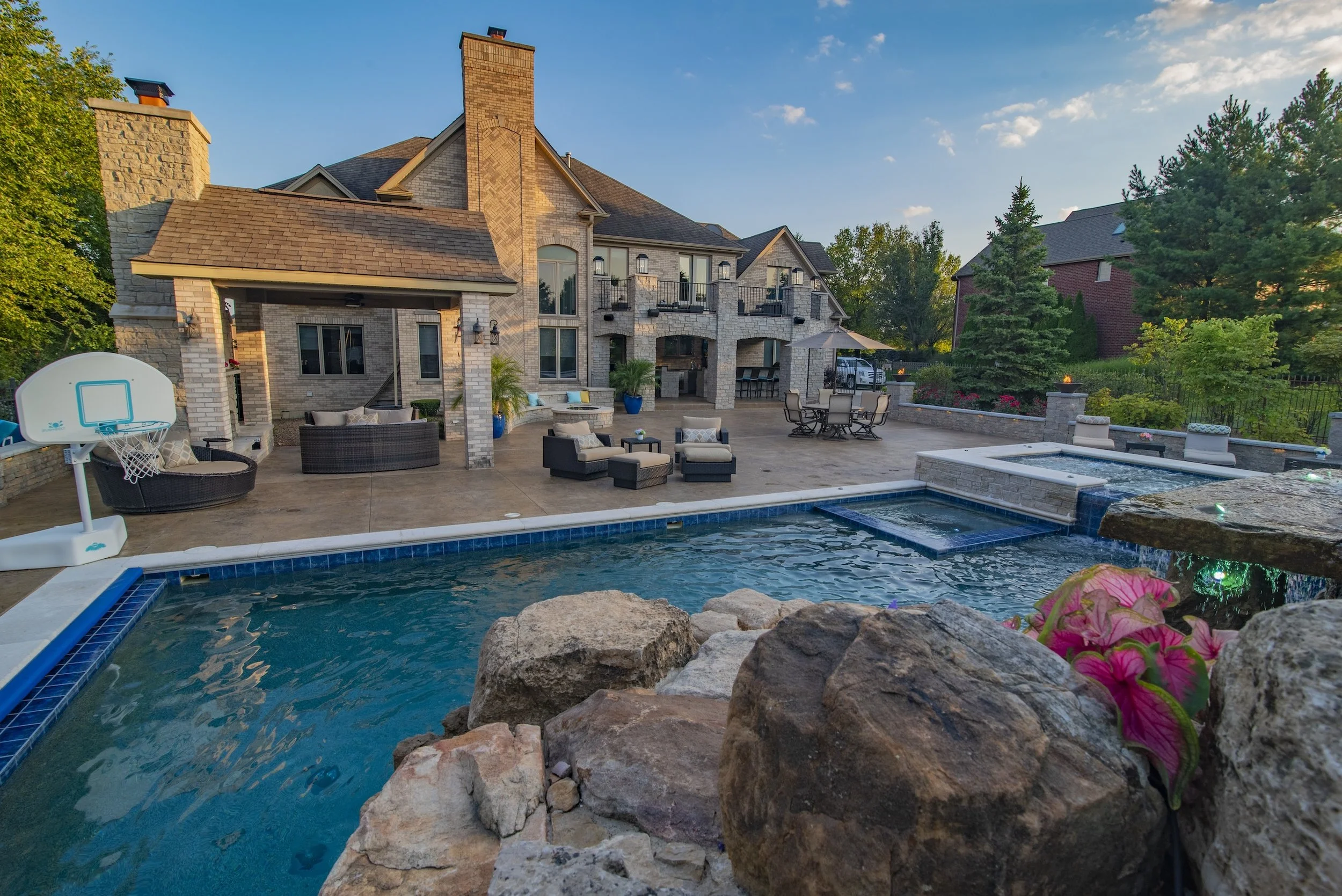Luxury house with brick exterior, patio furniture, and a backyard pool.