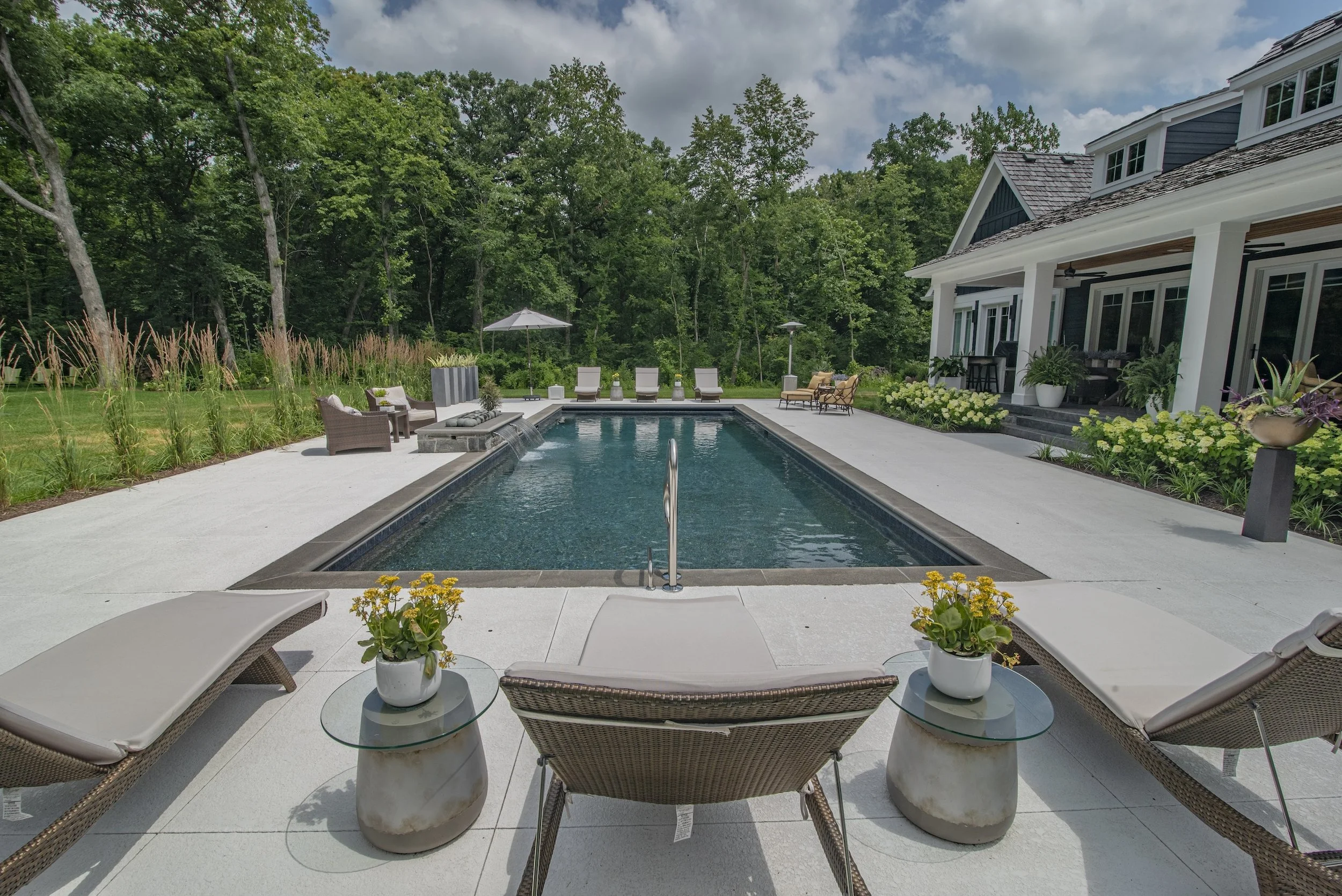 Luxury backyard with swimming pool, lounge chairs, patio area, and garden landscaping at a modern house.
