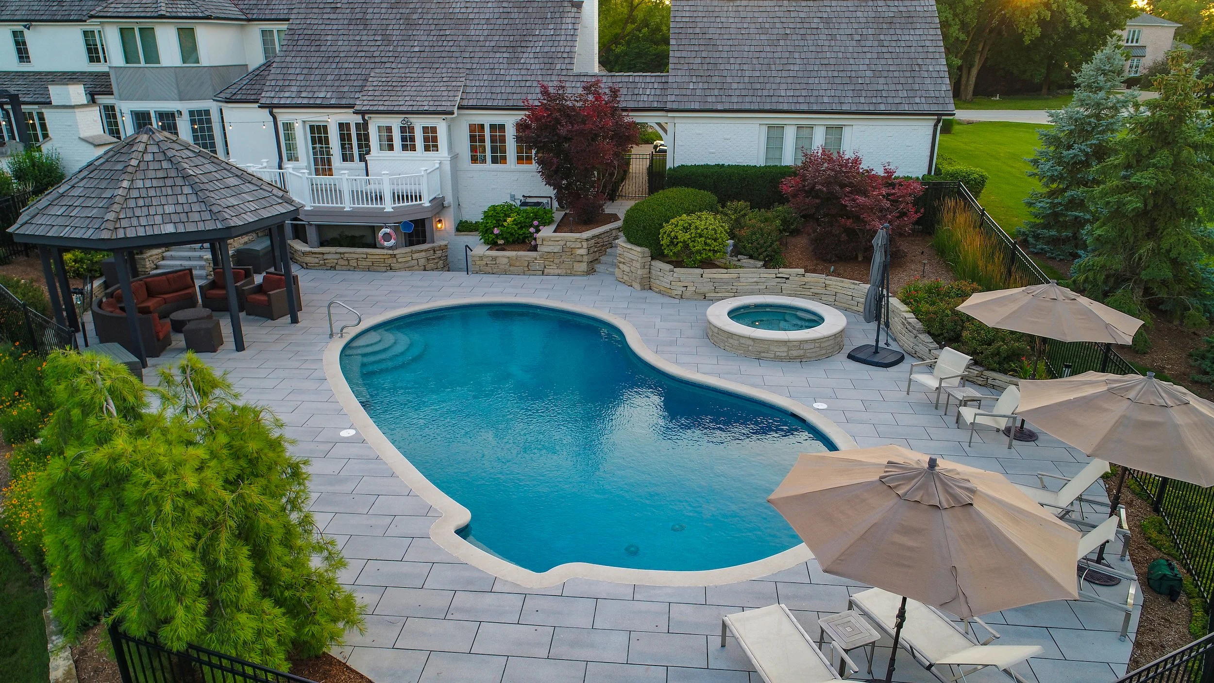 Backyard with a swimming pool, gazebo, hot tub, patio furniture, and surrounding landscaping.