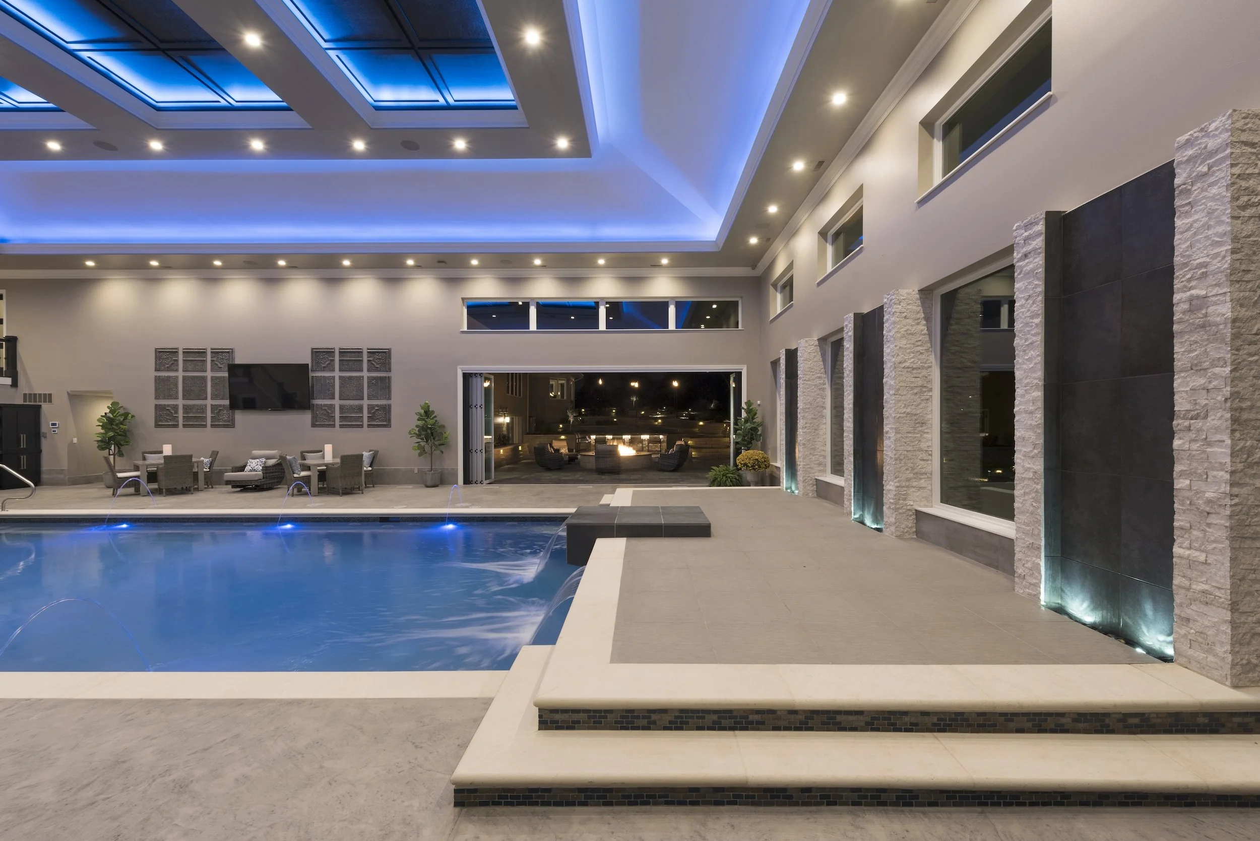 Luxurious indoor pool area with modern LED lighting, elegant seating, and a sleek design.
