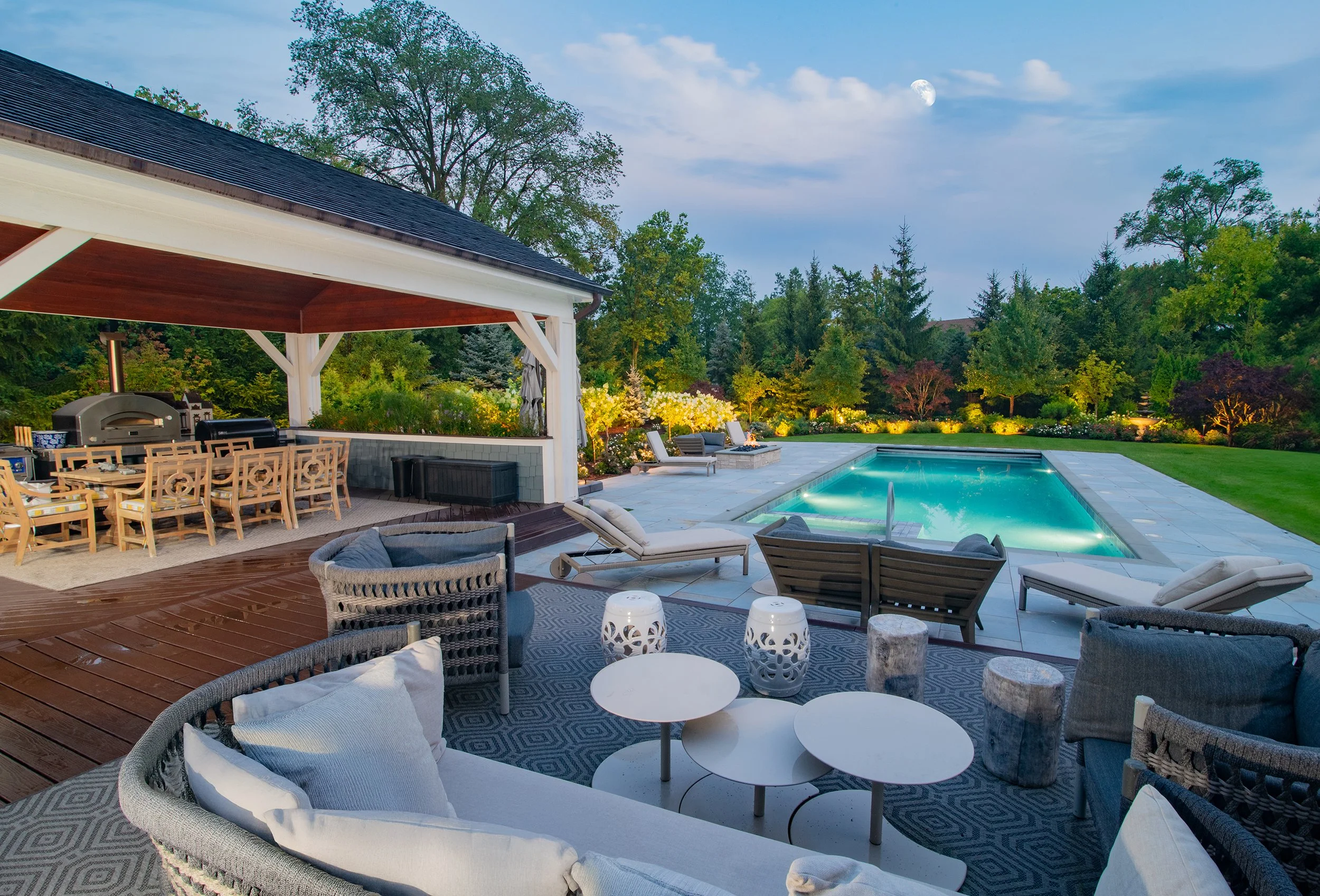 Luxurious geometric Barrington Pools inground pool at dusk with spa water features outdoor kitchen