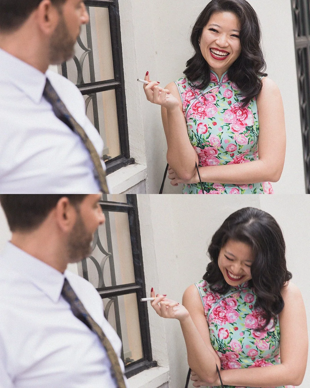 A woman with black wavy hair in a floral dress smiling and laughing while holding a cigarette, with a man in a white shirt and patterned tie partially visible. They are indoors, near a window, engaging in a friendly conversation.