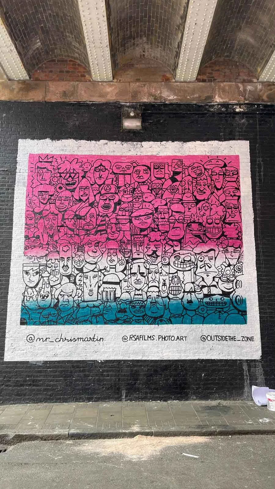Completed Shoreditch street mural by Chris Martin – finished large-scale wall painting under London railway arch featuring densely packed crowd of illustrated faces fading from pink to teal, street art installation