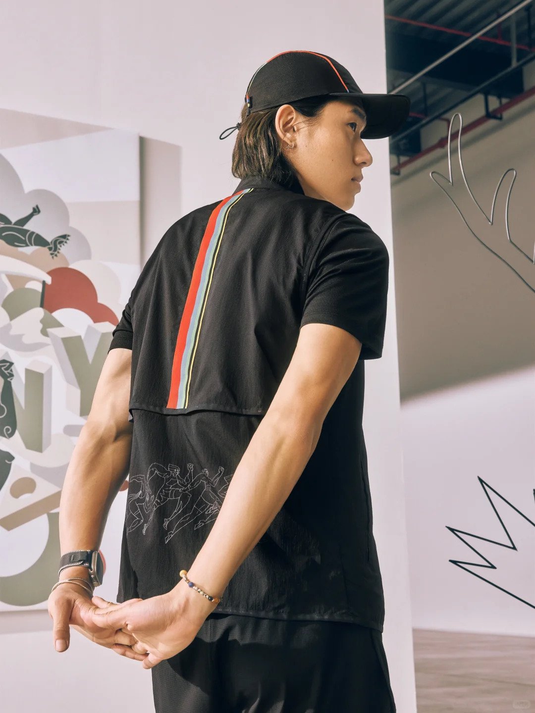 Saucony illustrated capsule collection collaboration with Chris Martin – featuring a man modelling a running jacket with the main design of retro cubist olympians   in a muted vintage colour palette commercial collaboration with Saucony in China