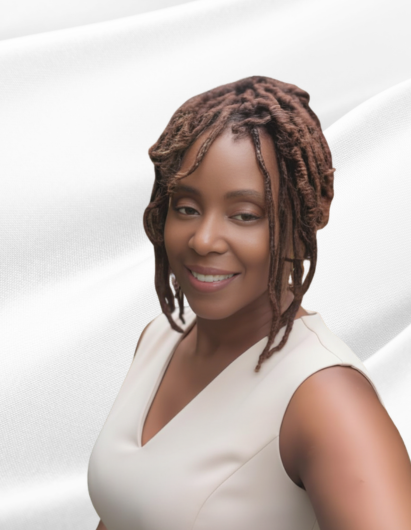 A woman with a warm, relaxed smile, posing against a soft, light-colored background that looks like gently folded fabric. She has medium-length, styled locs that frame her face, and she’s wearing a sleeveless, light beige or cream top