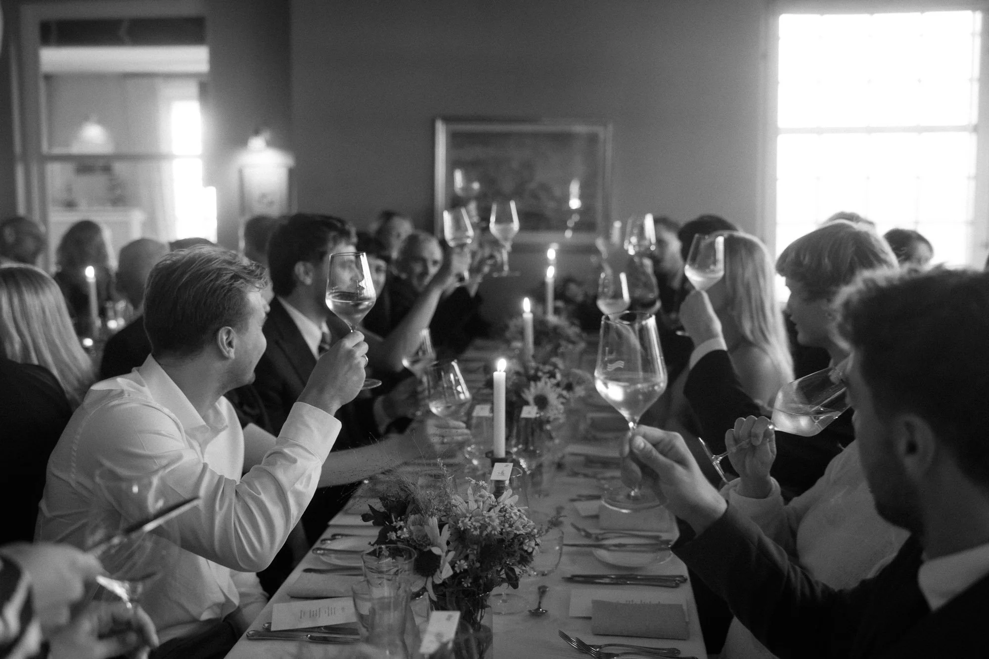 People gathered around a dining table raising wine glasses in a toast during a formal dinner celebration.