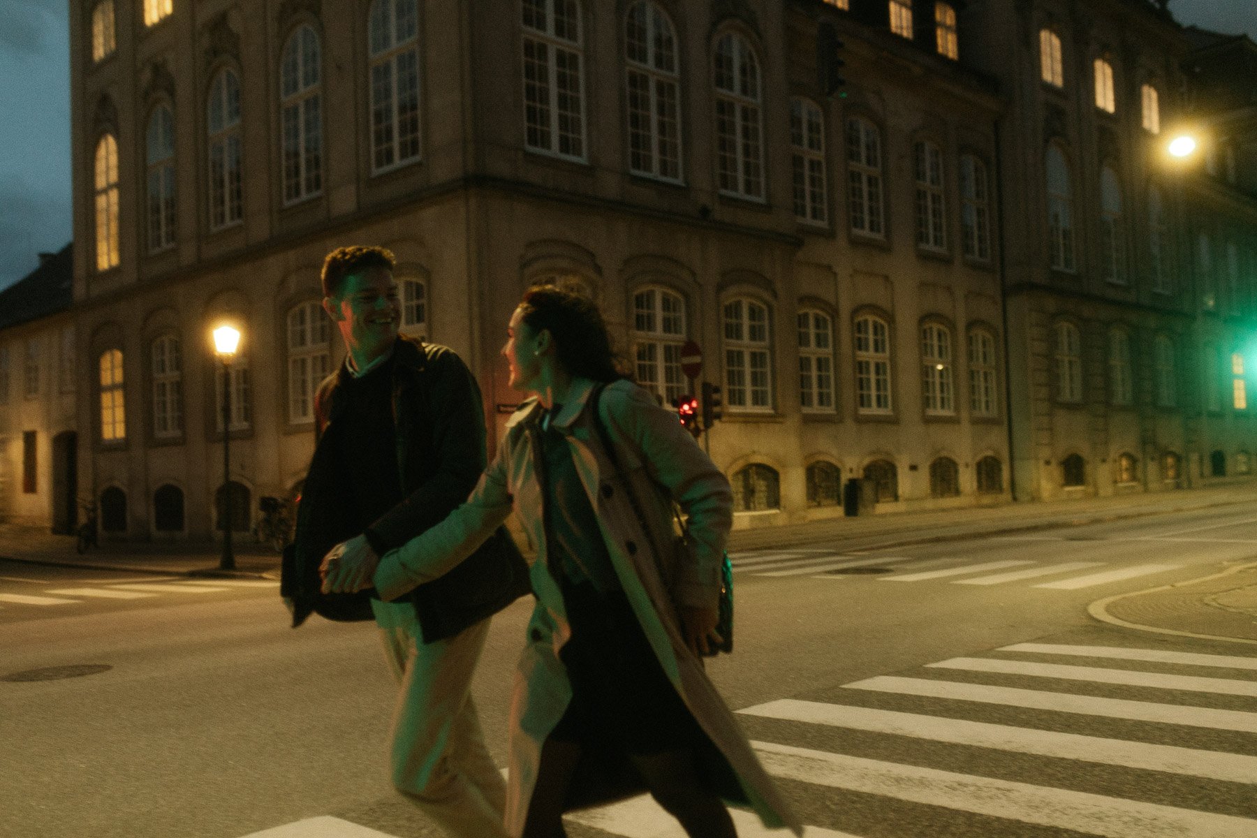 Couple entwined in love, holding hands, running around Copenhagen streets, as seen through the lens of a Copenhagen couple photographer