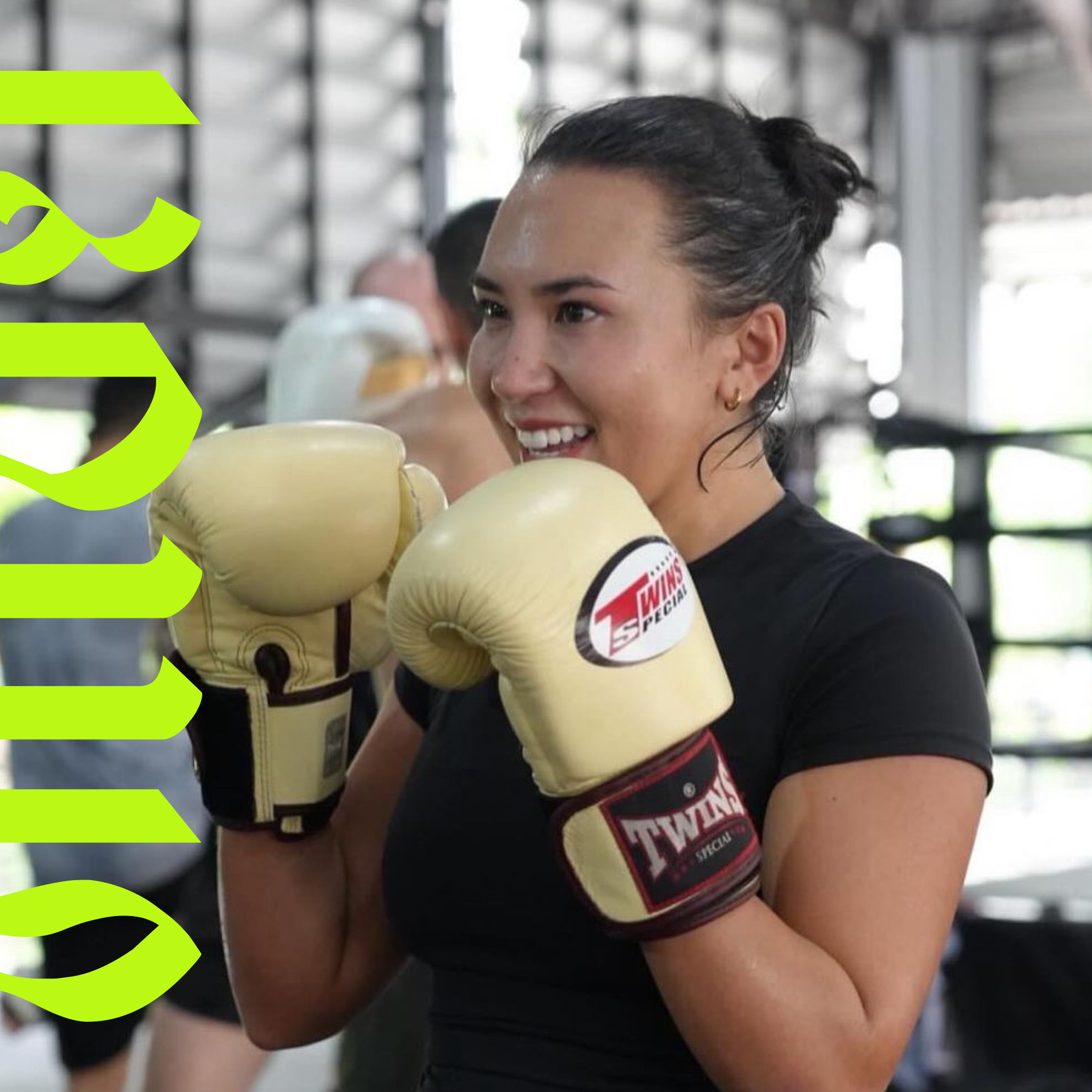 A young woman in boxing gloves practicing boxing at a gym.