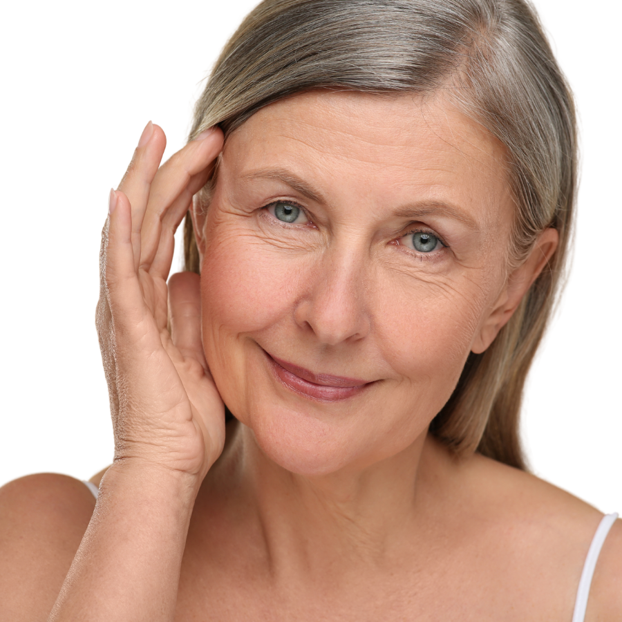 Close-up of an older woman with gray hair, blue eyes, and a slight smile, touching her face gently.