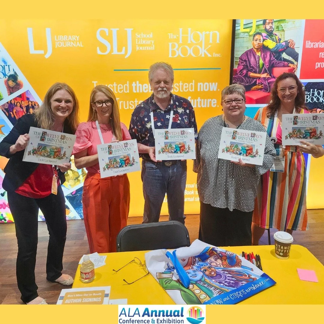 Group of five people holding books at the ALAA Annual Conference & Exhibition. They are standing in front of a bright yellow backdrop featuring logos of library journals and references to a book titled 'The Twelve Days of Christmas'. A table in front