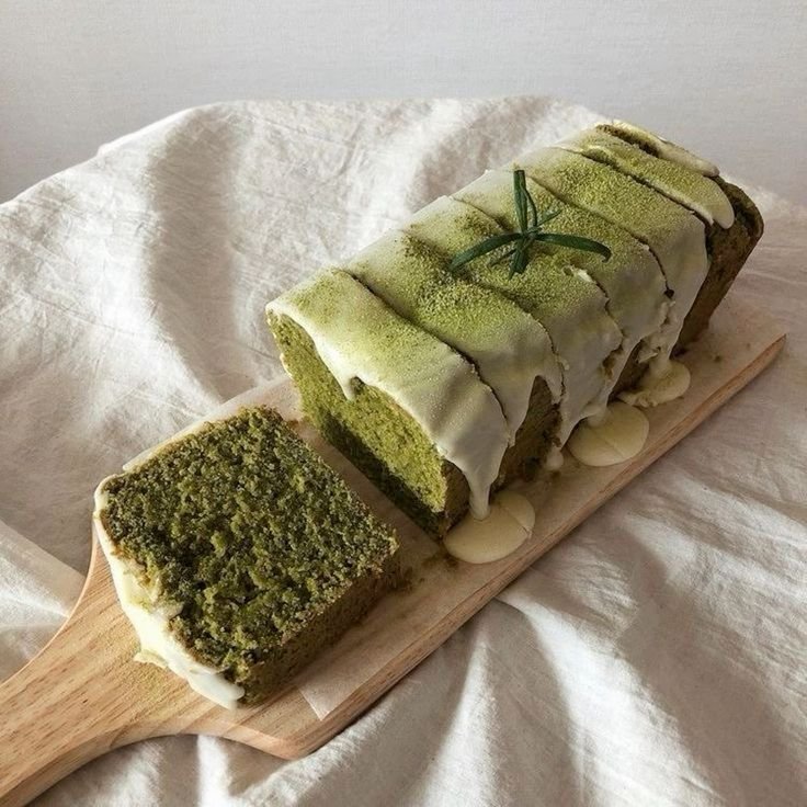 Green tea matcha loaf cake with white icing on wooden board
