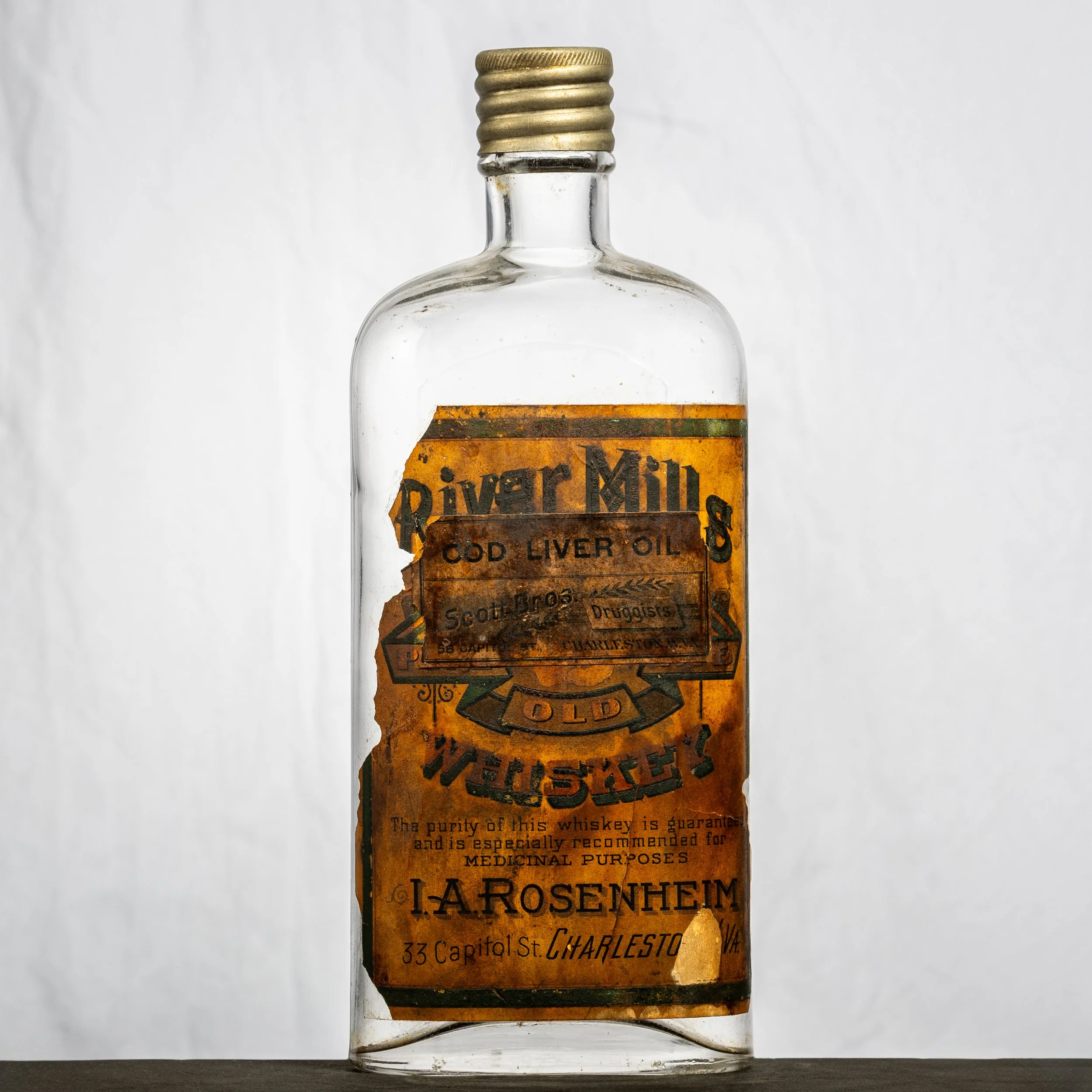 I.A. Rosenheim, River Mills Whiskey, Charleston labeled whiskey bottle. Has an over-stamped label from the Scott Bros. drug store for cod liver oil.