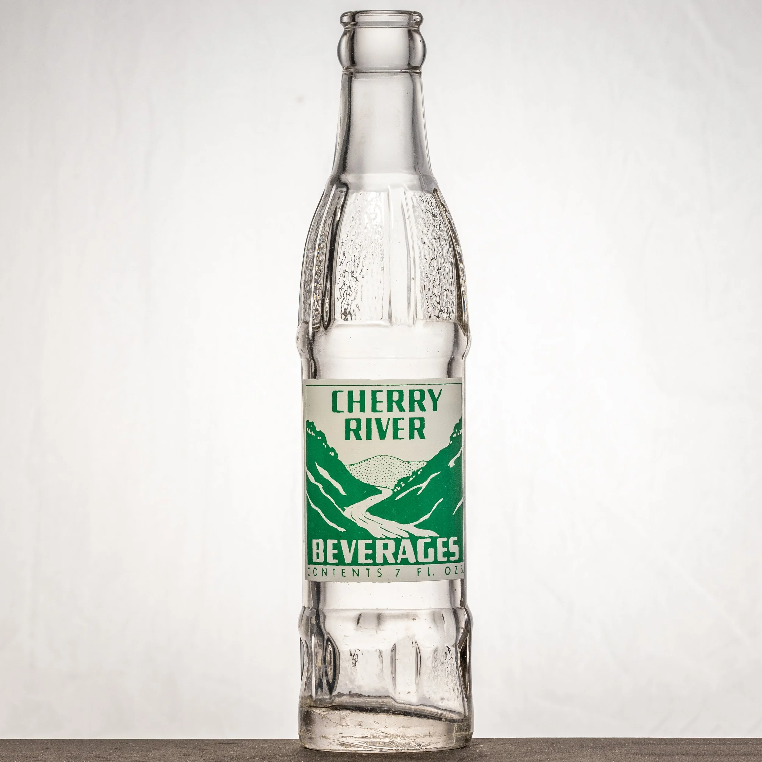 A Cherry River Beverages bottle from Nesbitt Bottling Co. of Belle, in Kanawha County. Painted green and white label. Front.