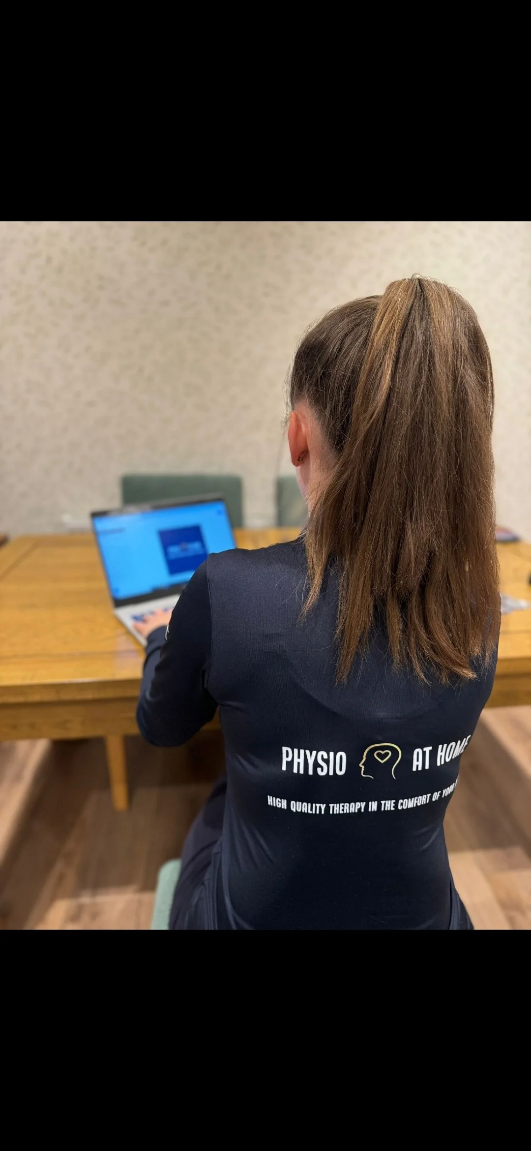 Physiotherapist working on a laptop at a desk.