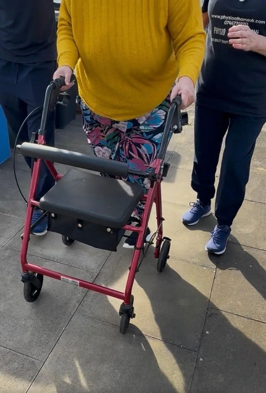 Patient walking with a walking aid and therapist