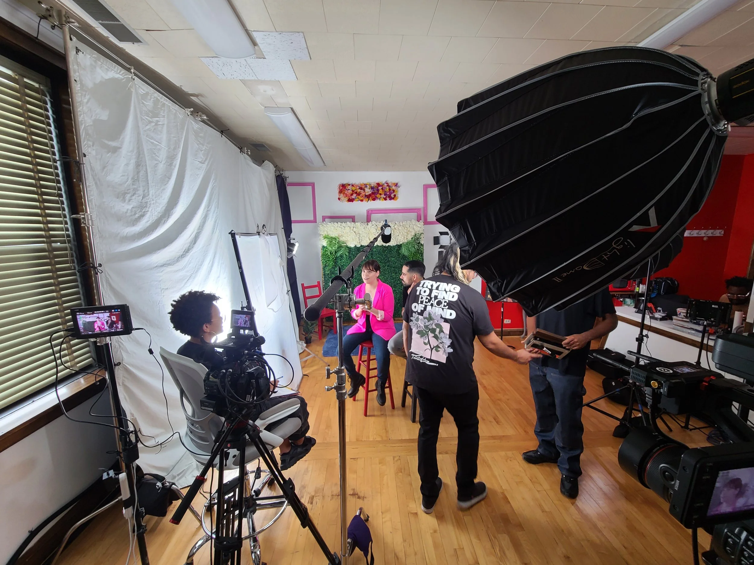 People filming a recorded interview or talk show in a studio with professional lighting and camera equipment.