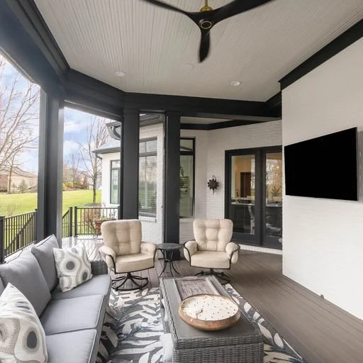 Covered outdoor patio with a gray sofa, two beige armchairs, a coffee table, and a wall-mounted TV.