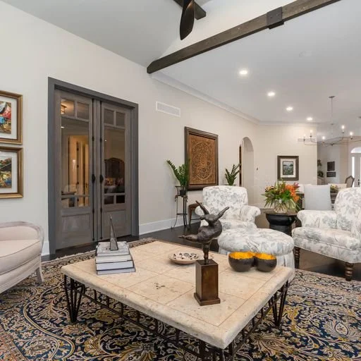 Living room with a large table, floral-patterned chairs, and decorative items