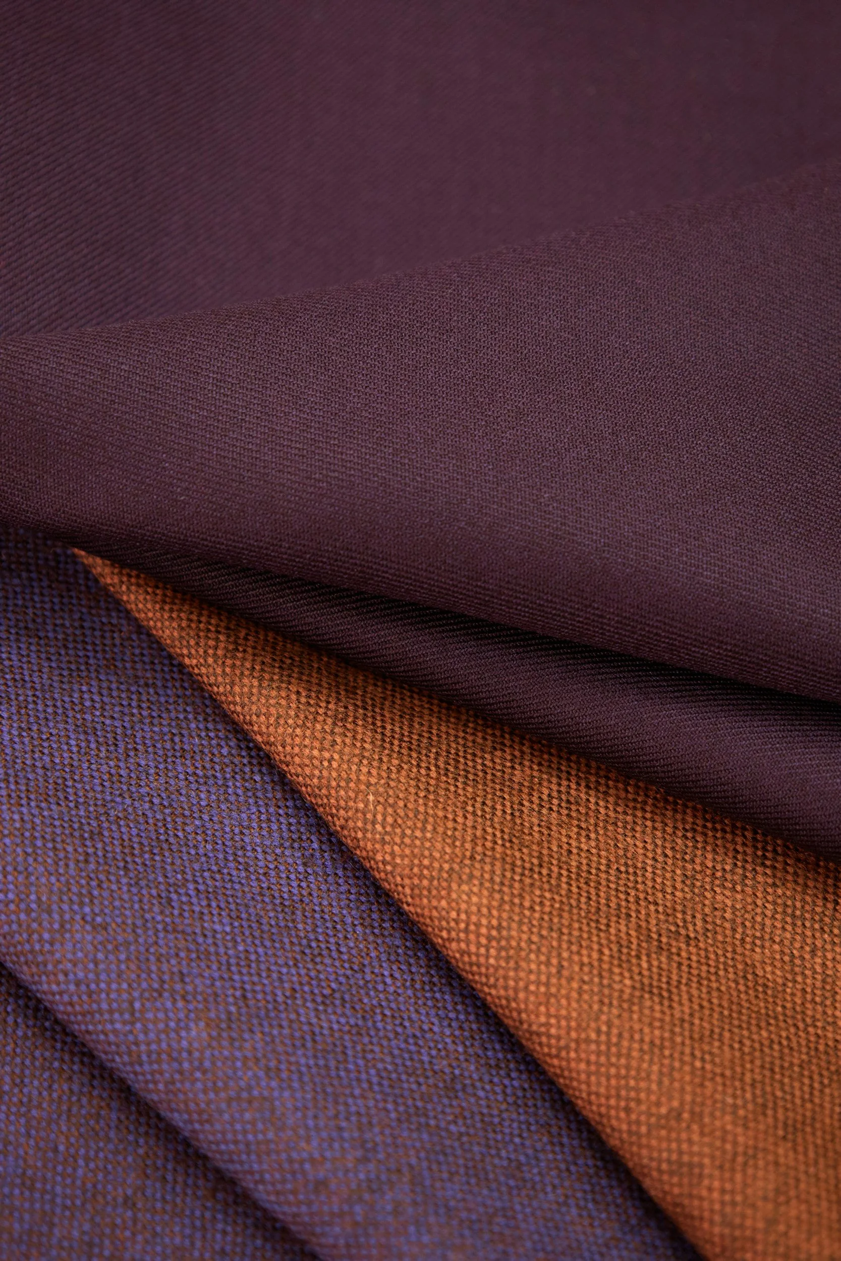 Close-up of folded fabric in burgundy, orange, and purple colors.