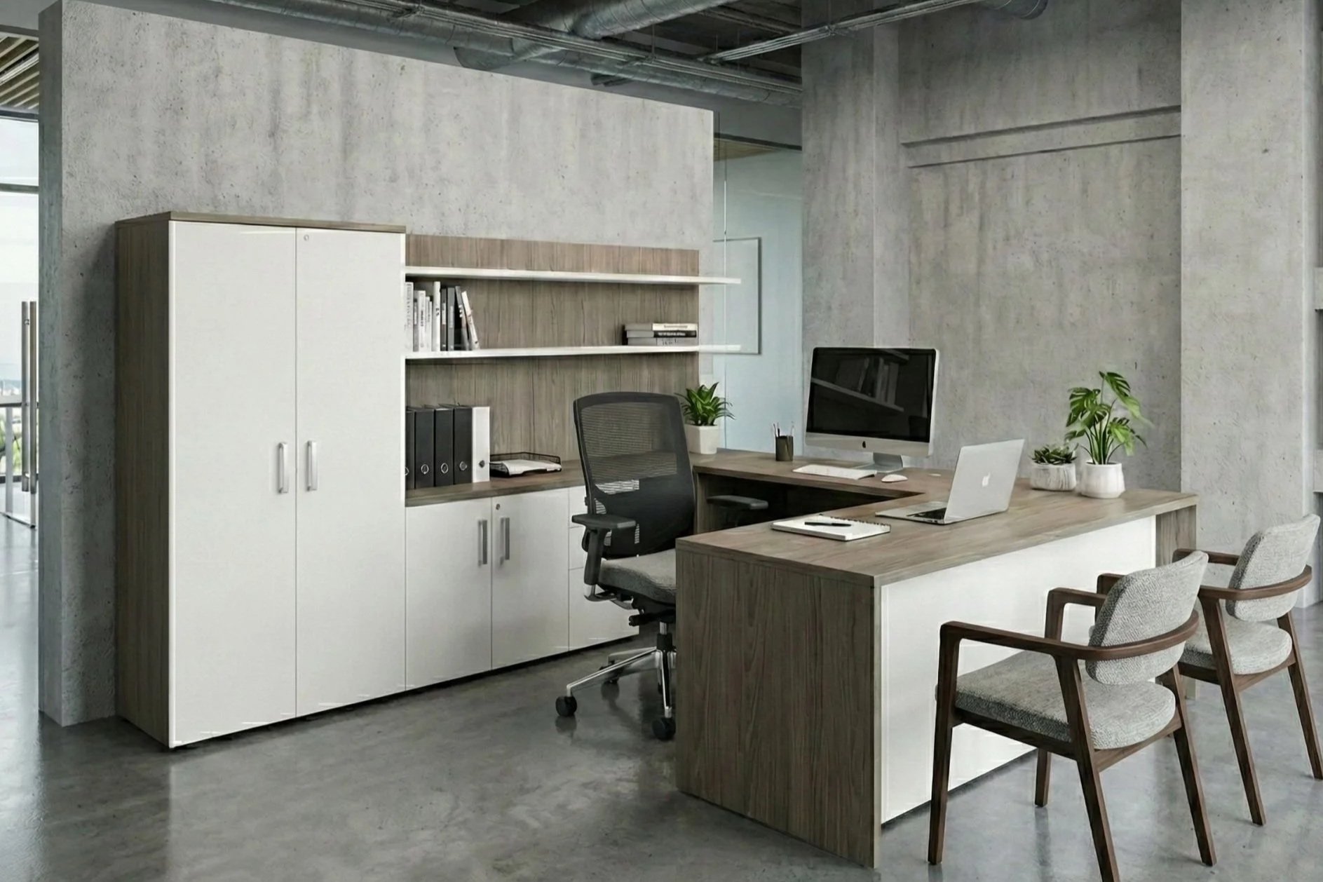 Modern office space with a wooden desk, computer, white cabinets, shelving with books and folders, potted plants, gray chairs, and an exposed concrete wall and ceiling.