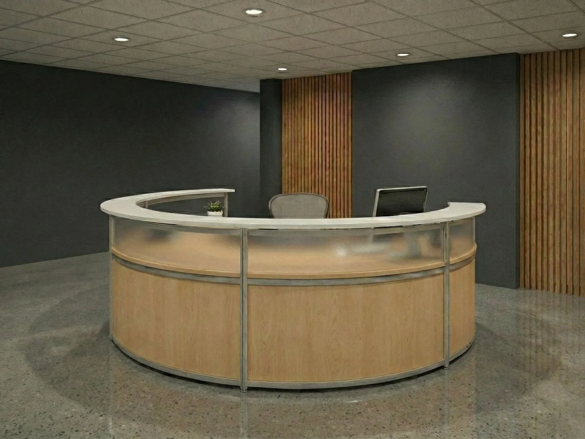 A curved reception desk made of light wood with metal framing, situated in a room with black walls, a ceiling with tile squares, and recessed lighting. There is a small potted plant on the desk and a gray office chair behind it.