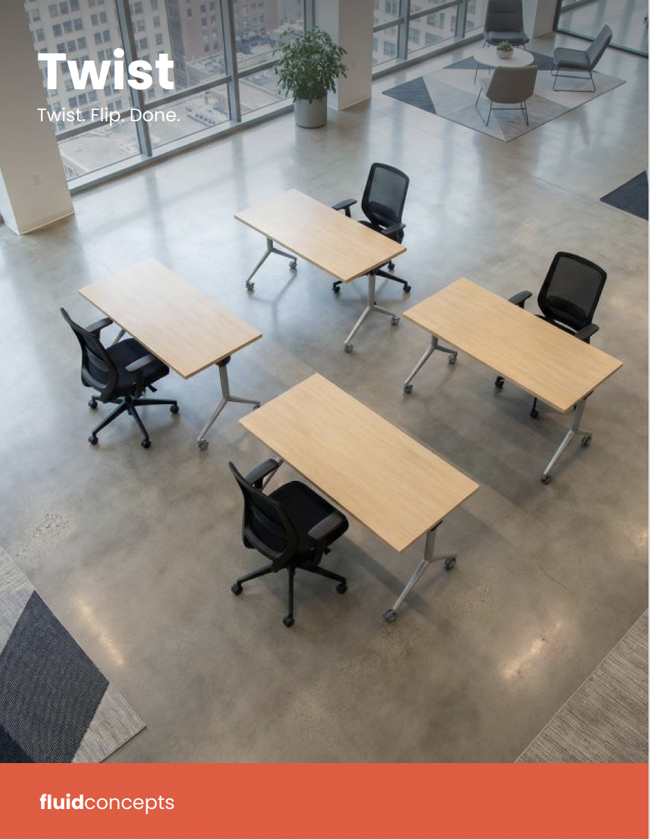 Interior view of a modern, empty office with four light wood desks and four black office chairs on a polished concrete floor, large windows revealing a cityscape, and a sitting area with two chairs and a small table in the corner.