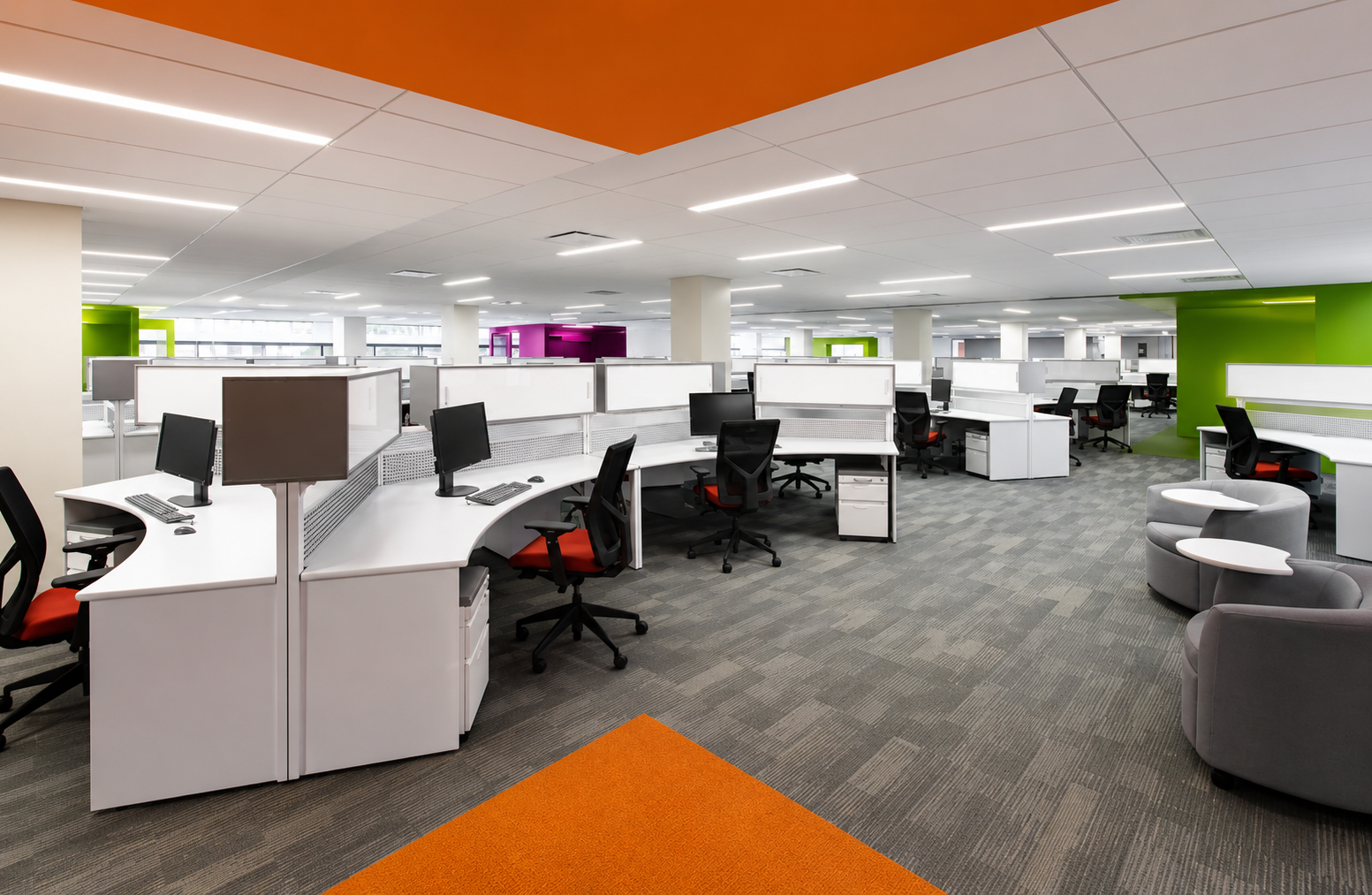 Empty modern office with white desks, black chairs, computer monitors, and colorful green, purple, and orange walls.