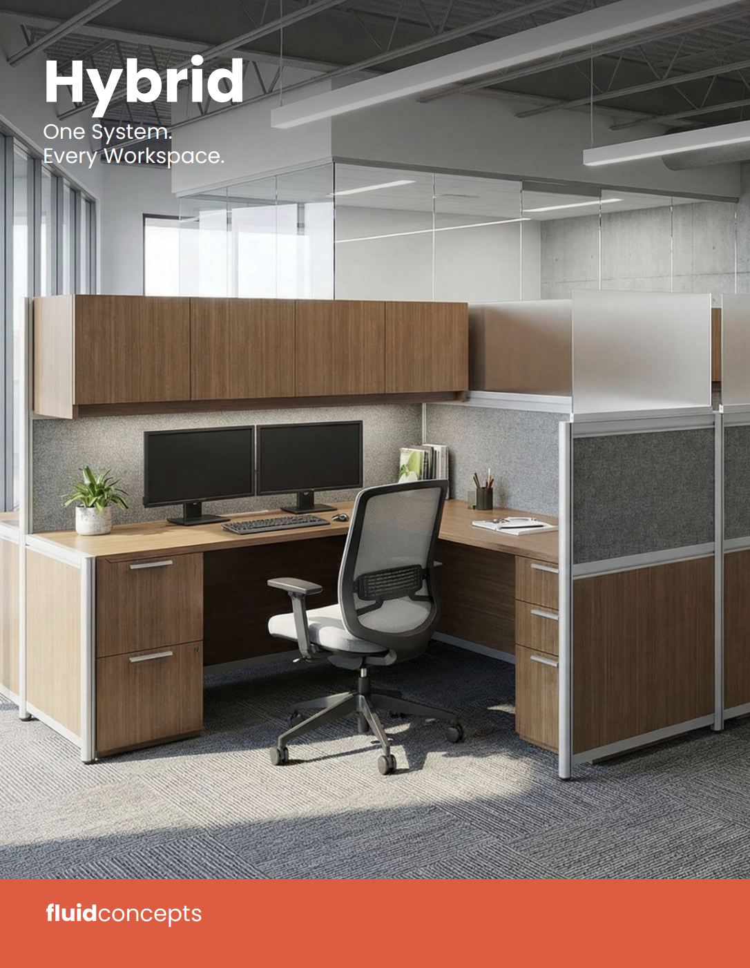 Modern office cubicle with wooden desk, dual monitors, office chair, small plant, and office supplies, in an open workspace with glass partitions.