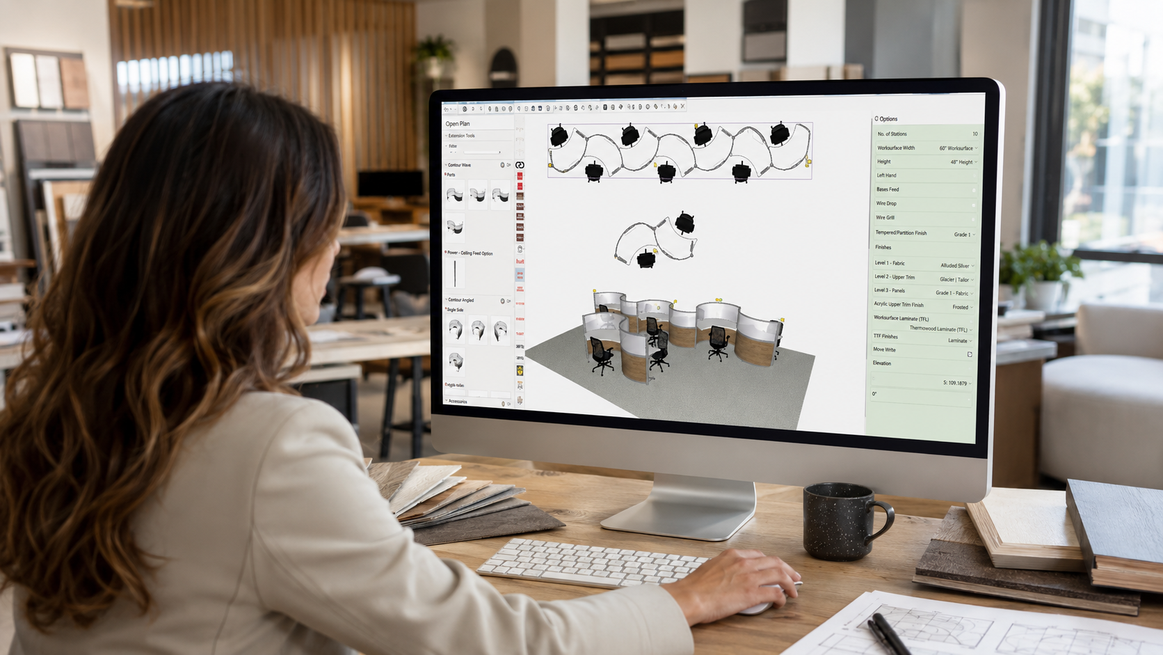 A woman at a desk working on a computer with architectural design software displaying 3D office furniture layout. The workspace has wooden desks, books, a coffee mug, and a window with natural light.