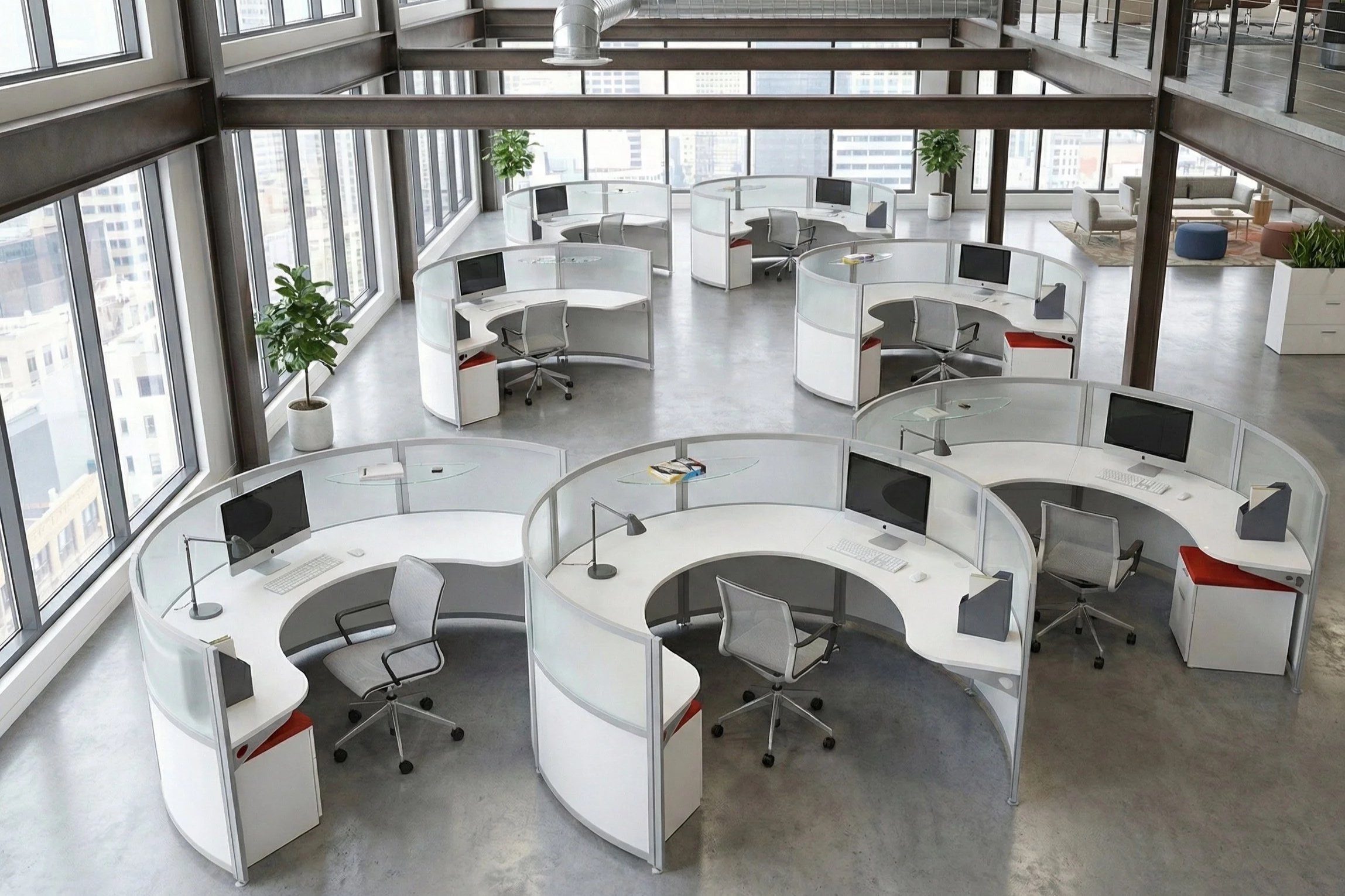 Open-plan modern office space with circular desks, each equipped with computers and office chairs, large windows providing natural light, and some lounge seating in the background.