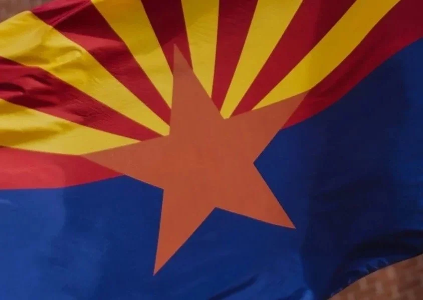 Close-up of the Arizona state flag showing a red star with yellow and red rays in the background and a blue section at the bottom.