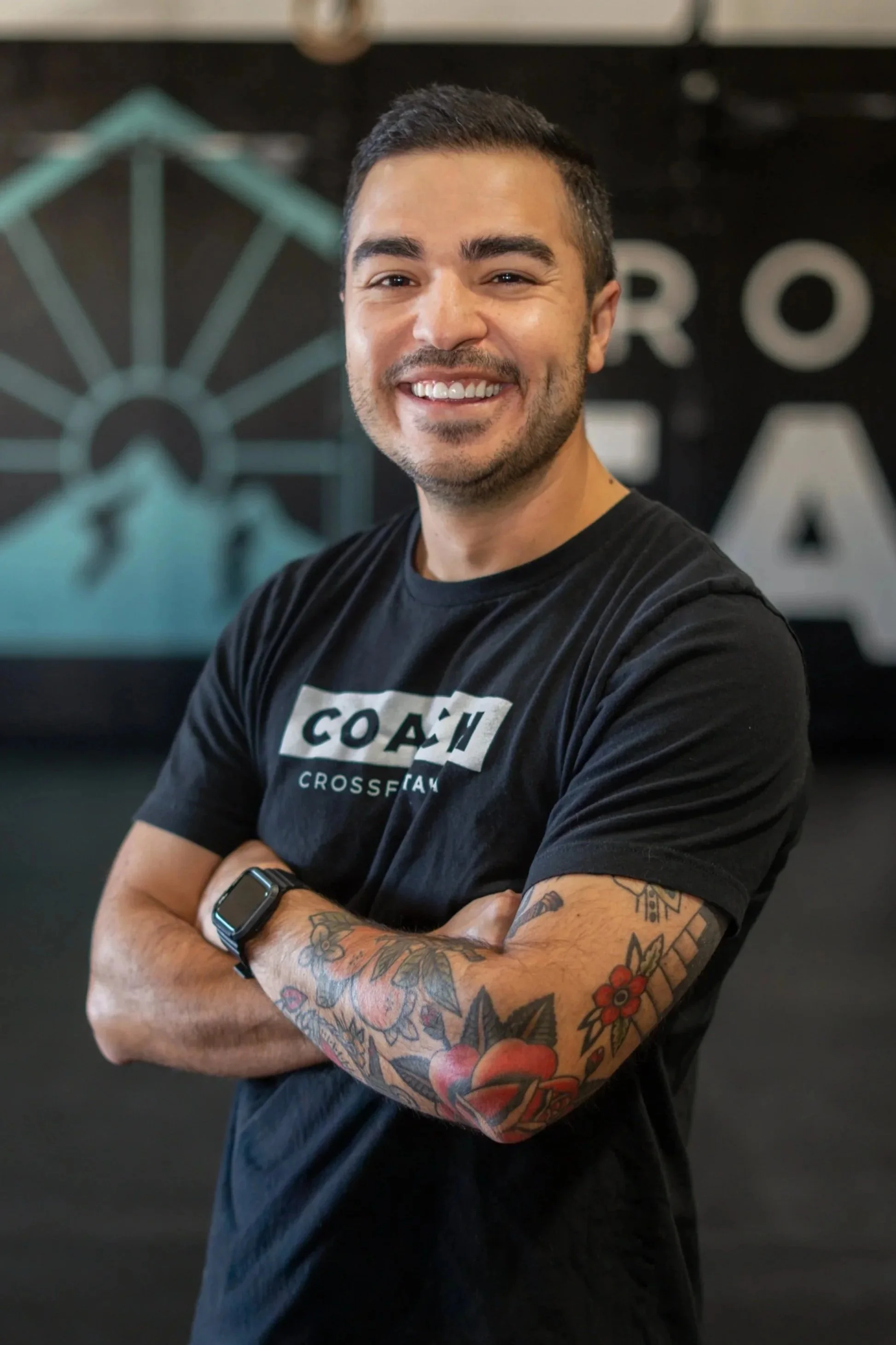 Man lying on gym floor smiling, wearing tie-dye shirt and shorts