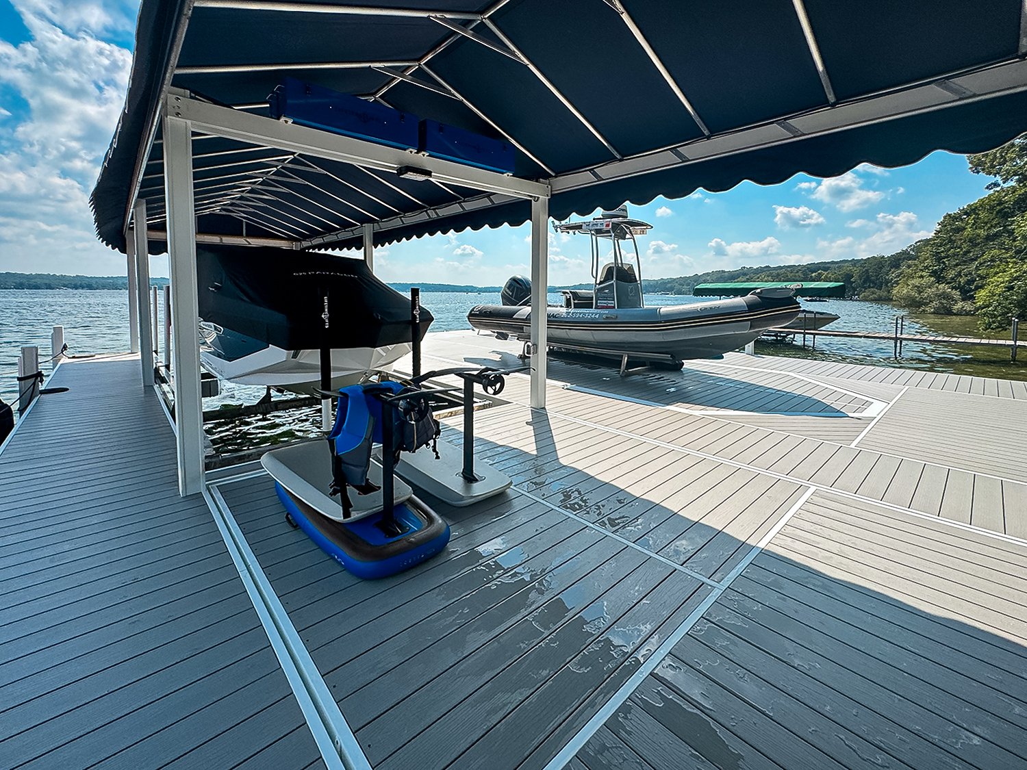 Boathouse dock with two boats, water, and blue sky with clouds.