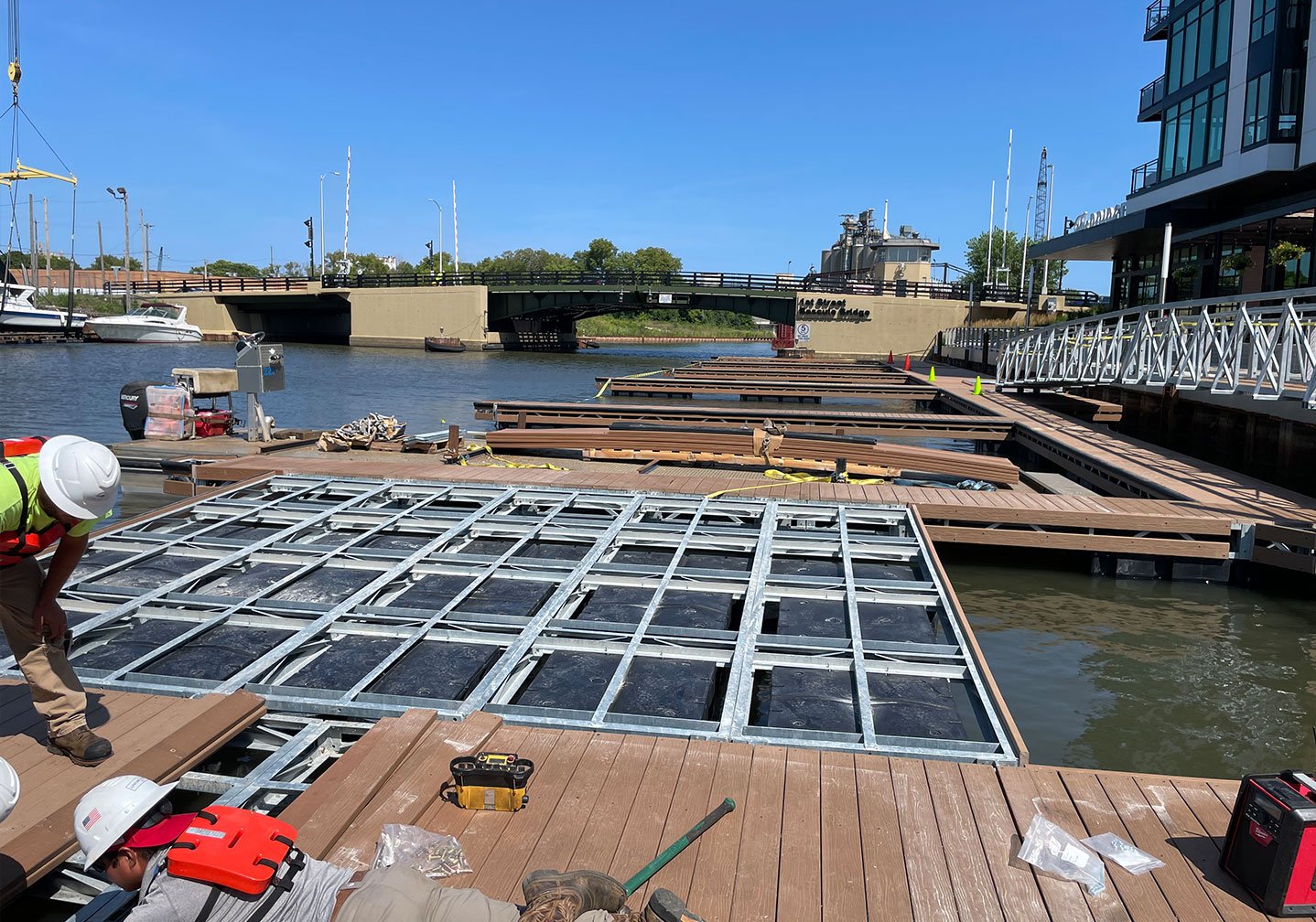   Gangway Connection to Dock System:  
A newly installed aluminum gangway provides access from shore to the floating dock system, with additional dock sections staged nearby.