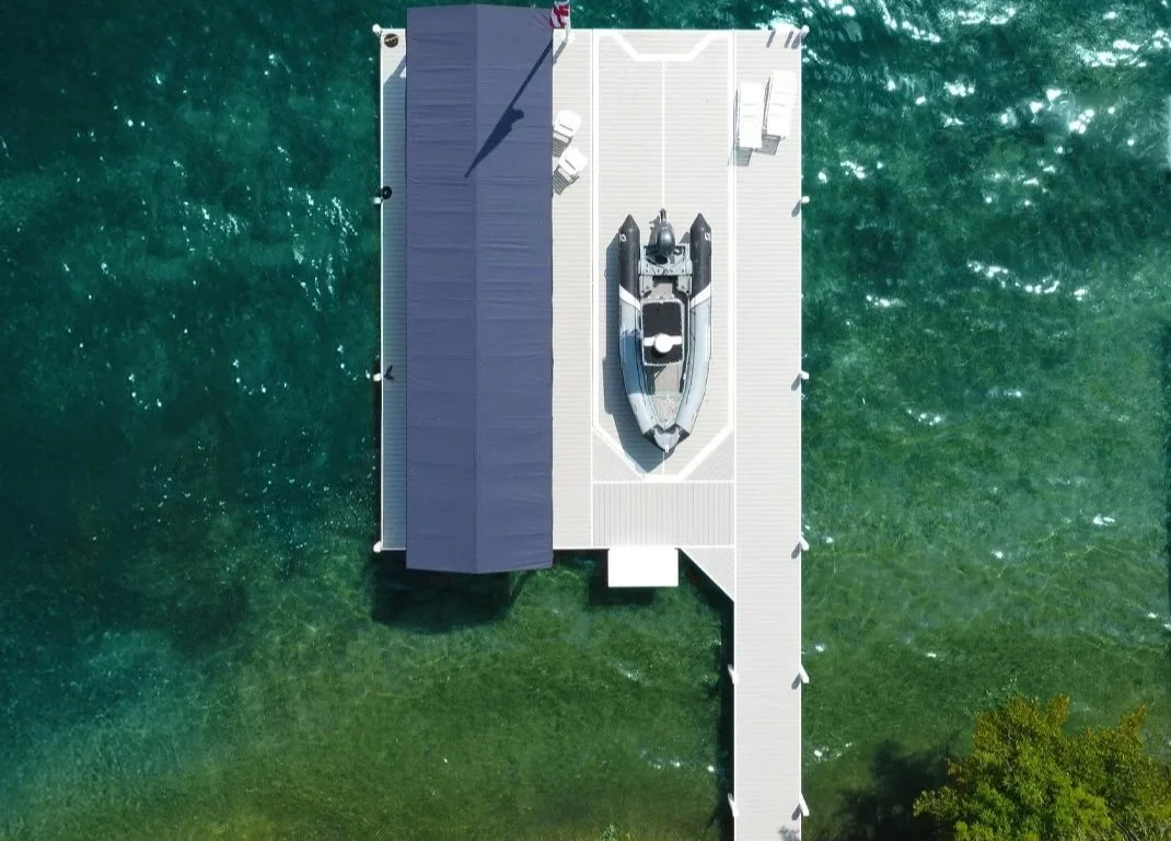 Aerial view of a Lifetime All Seasons HD Pier on Geneva Lake featuring a covered boat lift, waterfront lounge area, and floating swim raft.