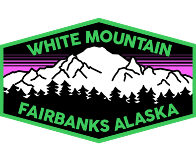 Logo for White Mountain Fairbanks Alaska featuring a mountain range silhouette, pine trees, and purple and green accents.