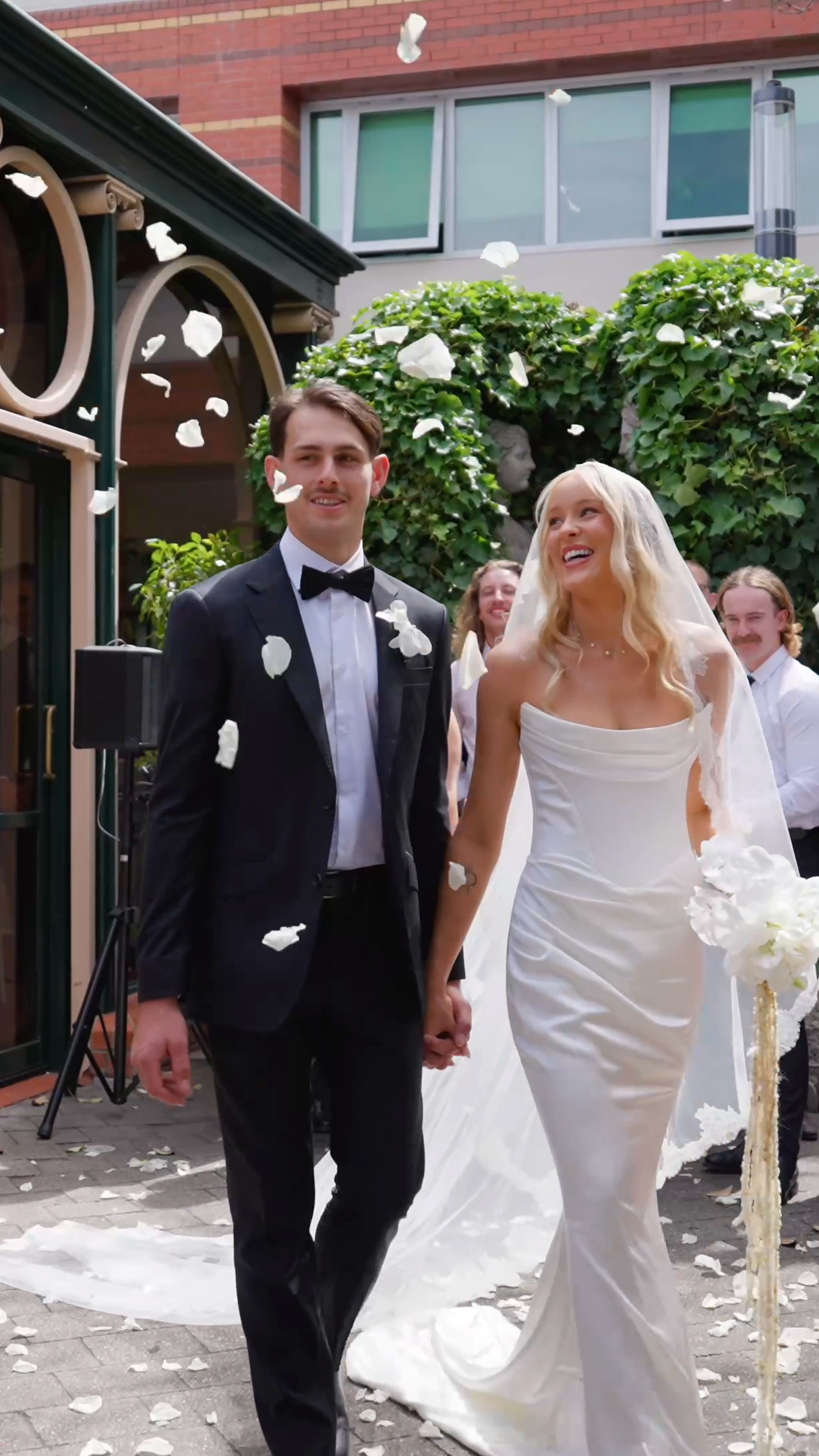Bride and groom walking out through a petal toss in the courtyard at Ayers House, Adelaide