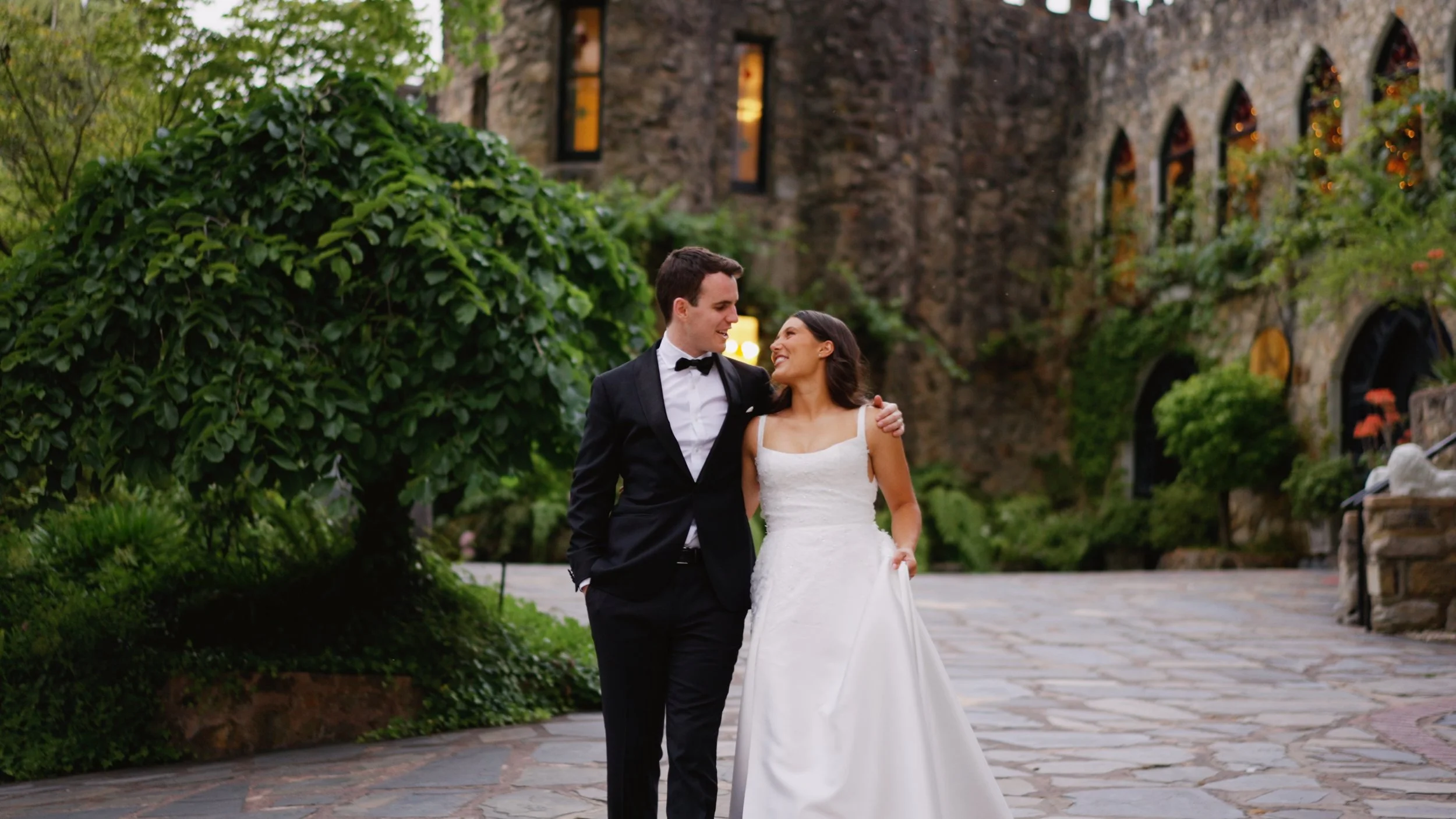 Bride and groom arm in arm outside the stone castle at The Manor Basket Range