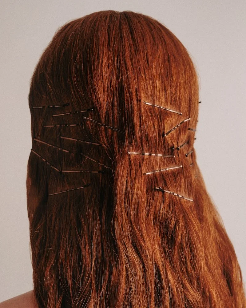 Woman with vibrant red hair styled by a JCI hair art design student during a practical session.