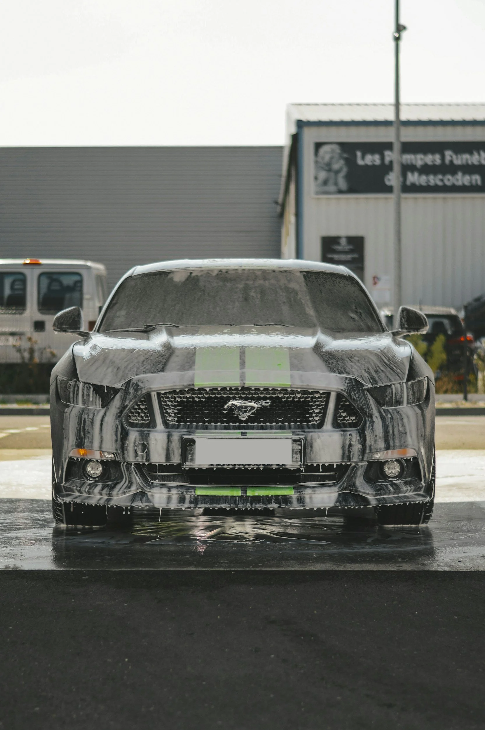 Front view of a car being covered in soap at a car wash.