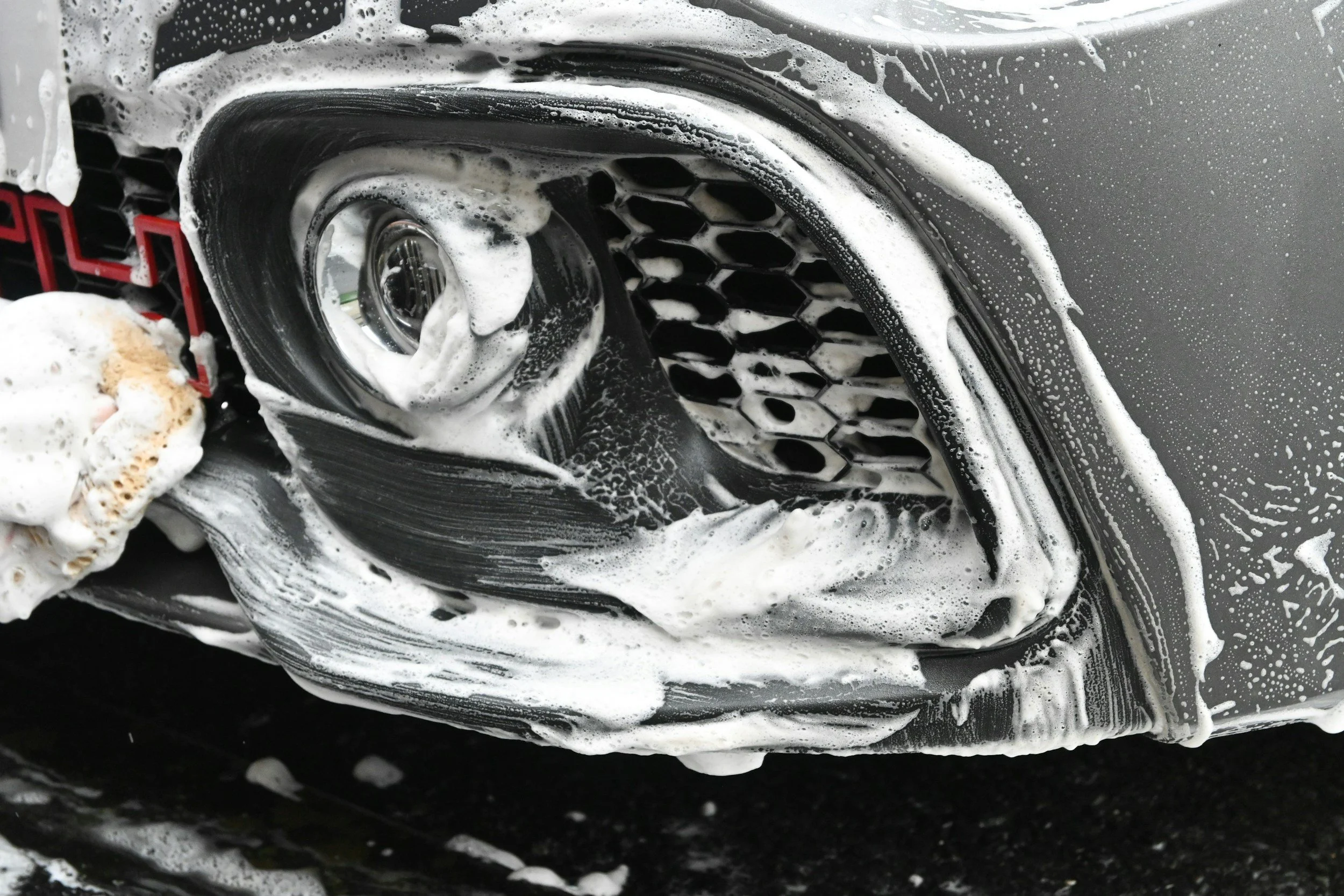 Car covered in soap suds during a professional mobile car wash and detailing service.