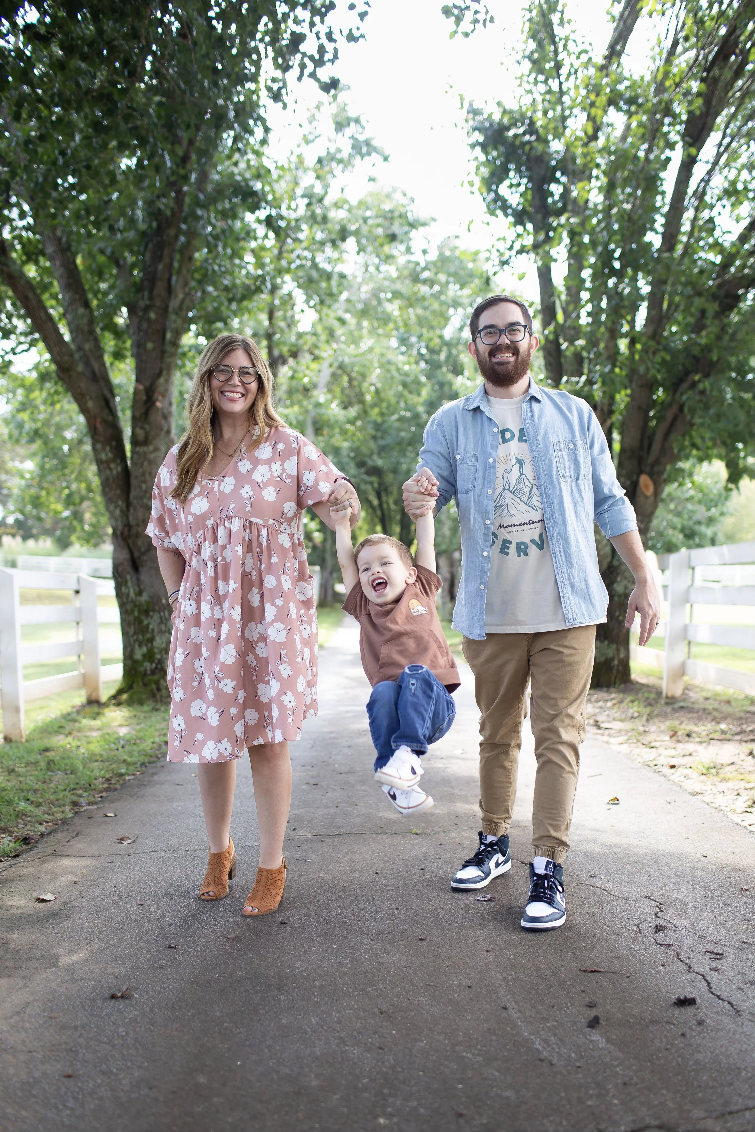 Adoptive parents, Jimmy and Kristen, swinging their son on a walk
