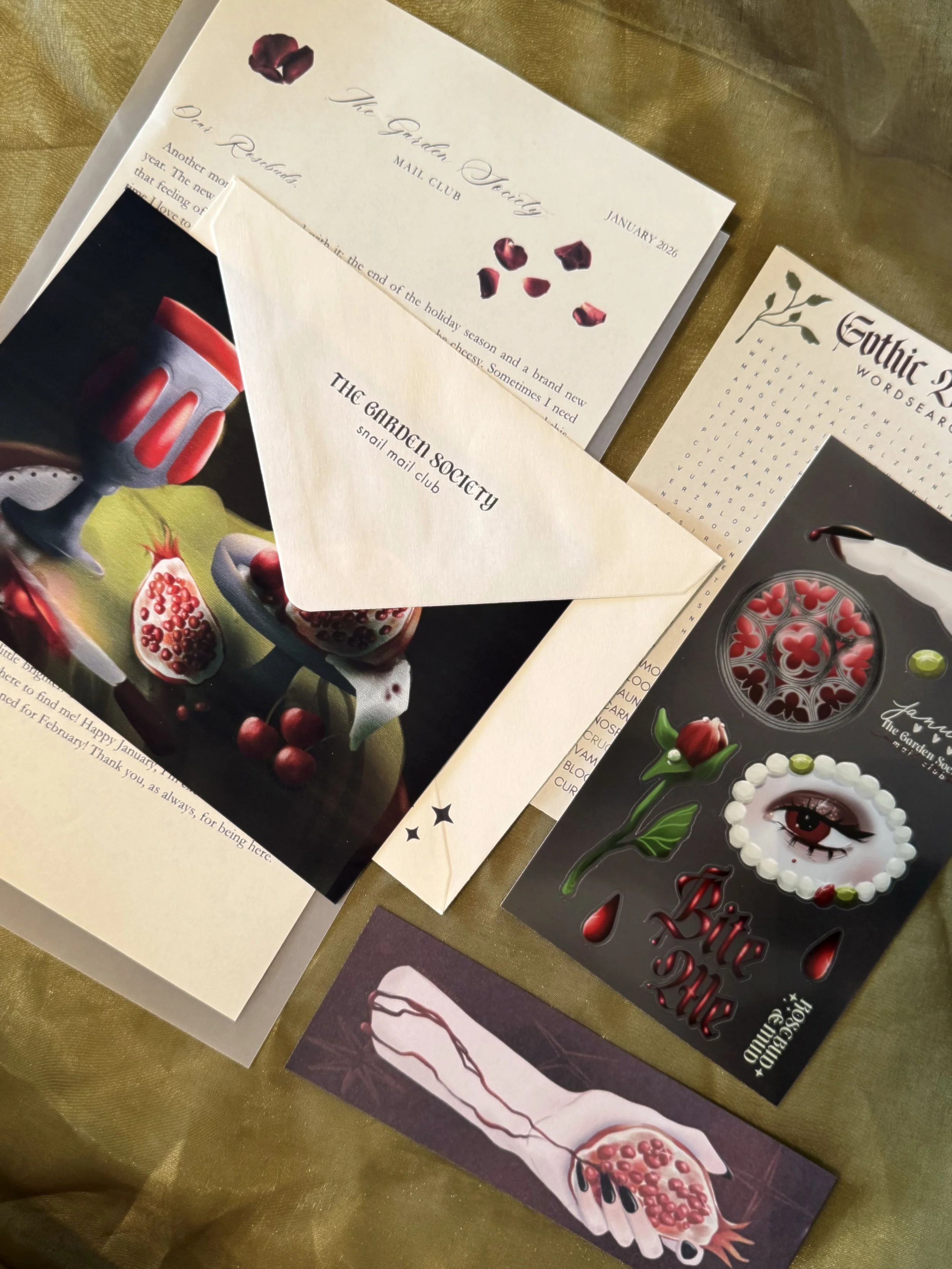 a flat lay photo of a vampiric art print, sticker sheet, bookmark, and letter for the mail club theme of the month. 