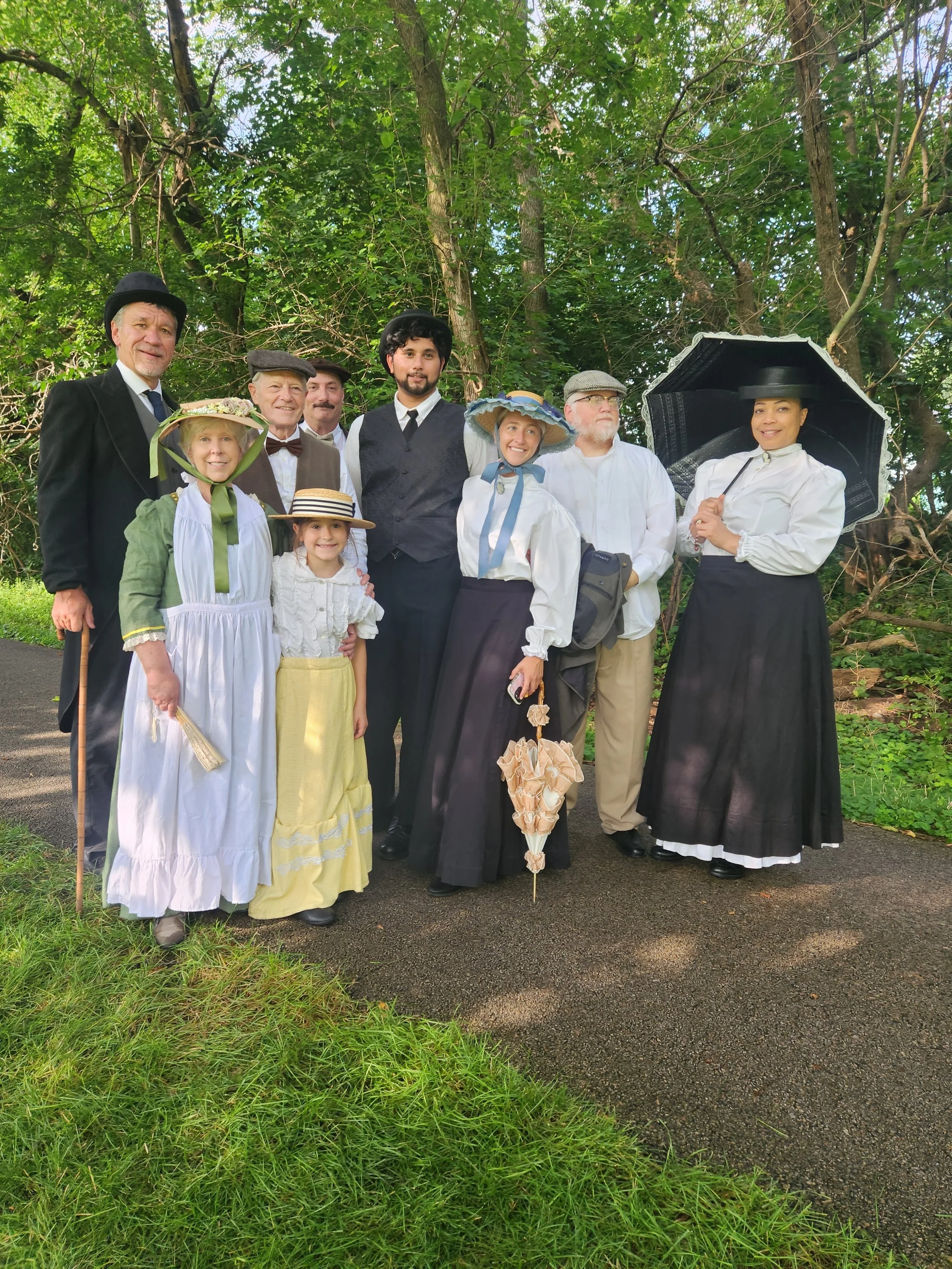 A group photo of nine people dressed in 19th century attire.