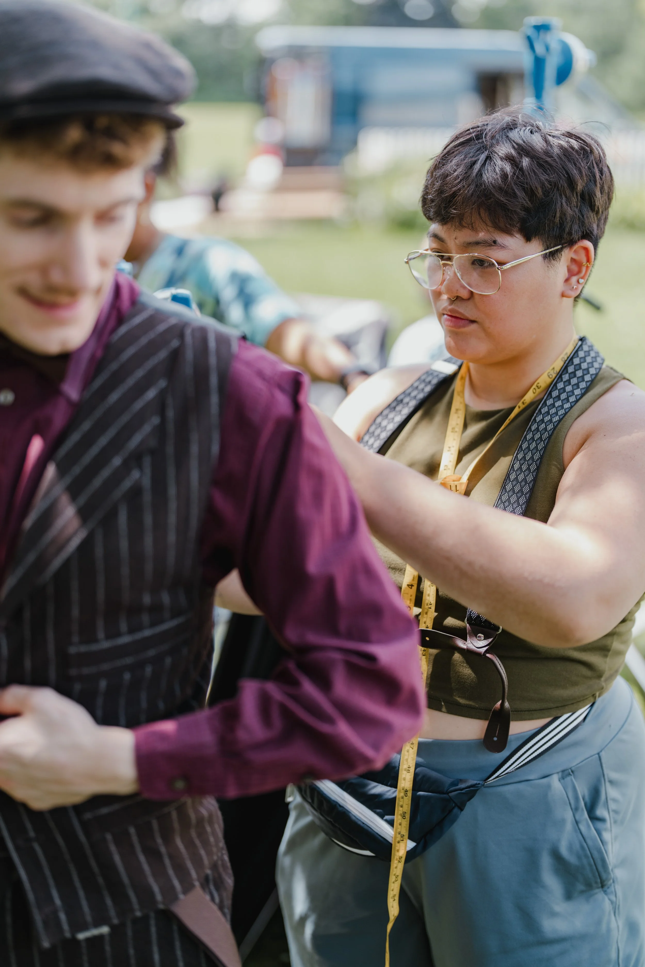 Regina on set with measuring tape around neck, fitting an actor in a period piece.
