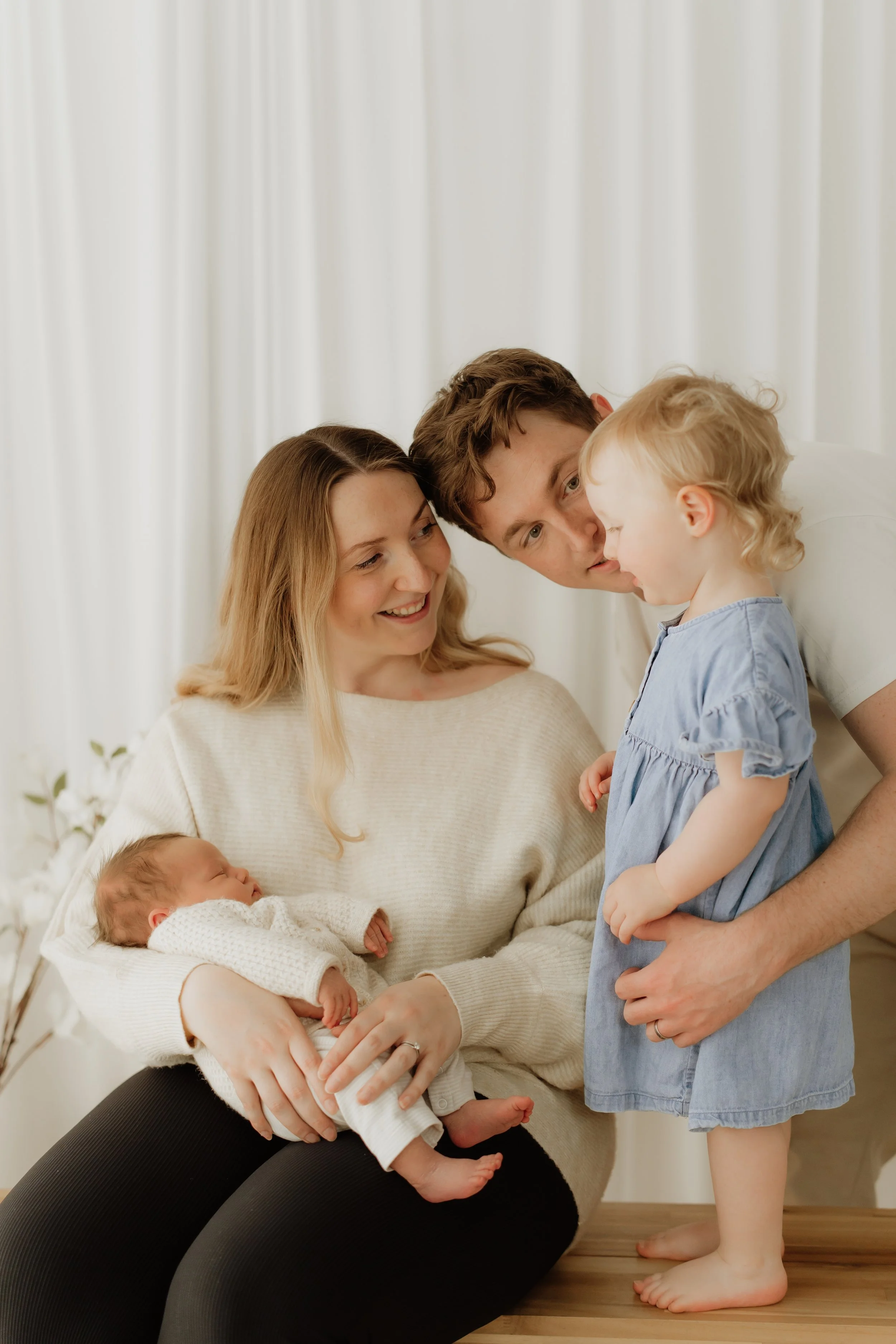 mum holds newborn baby as dad holds older sister