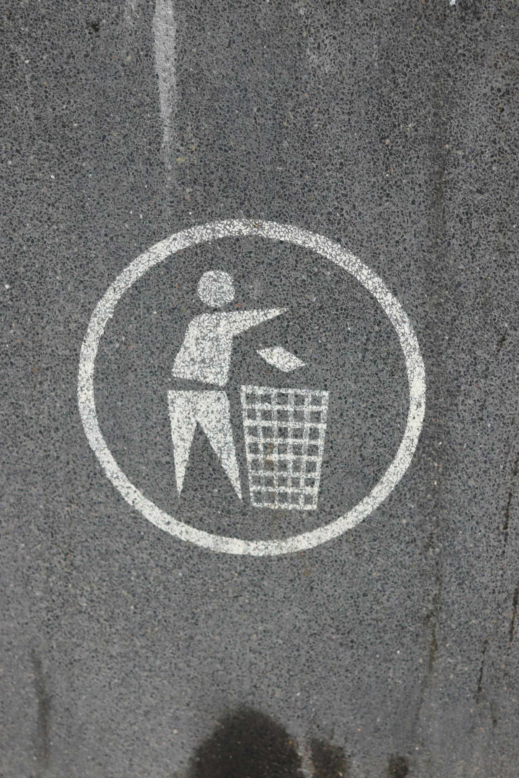Minimal waste icon on pavement representing less plastic and everyday sustainability.